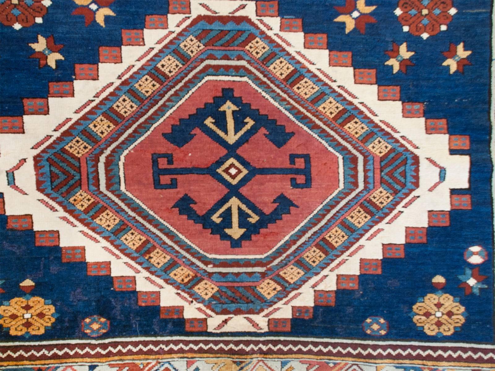 A unique mid-20th century Russian Kazak rug with three wonderful and large multicolored vegetable dyed diamond medallions with a simple geometric design, amidst a field of stylized flowers on a beautiful indigo background. The border is simple with