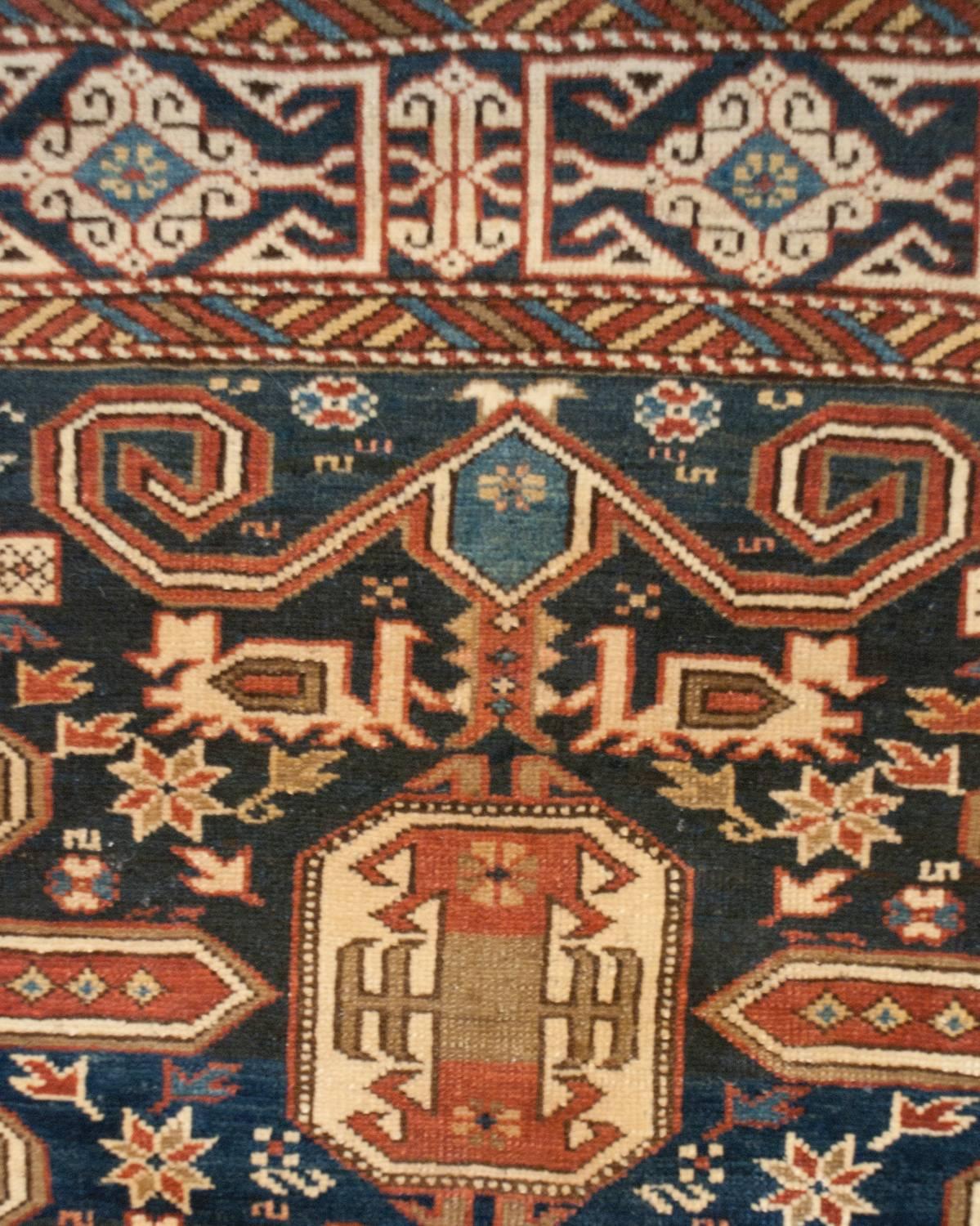 Un affascinante tappeto caucasico perpetuo della fine del XIX secolo con un incredibile motivo tribale di fiori e foglie stilizzati e galline sapientemente tessute in lane cremisi, indaco e naturali, il tutto su un ricco sfondo indaco. Il bordo è