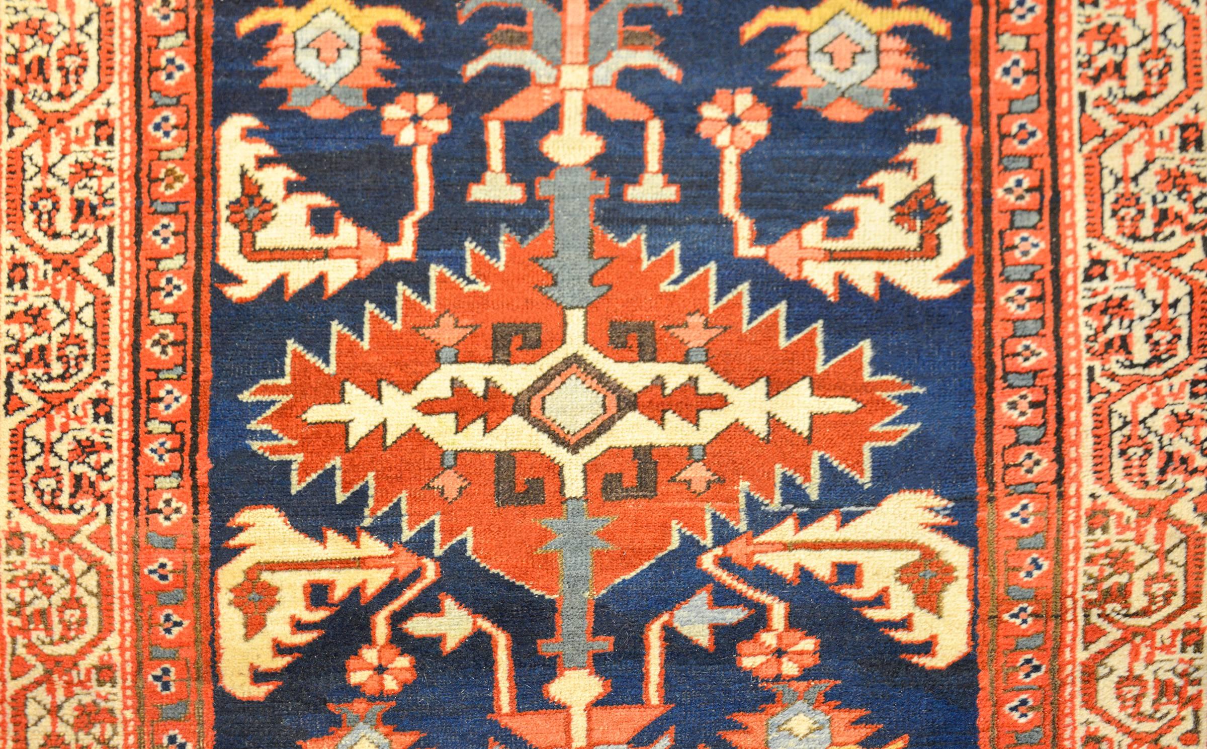 An exceptional late first quarter century Persian Bakshaish runner with incredible tribal geometric medallions woven in wonderful crimson, salmon, amidst scrolling vines and flowers on a dark indigo background. The border is wonderful with three
