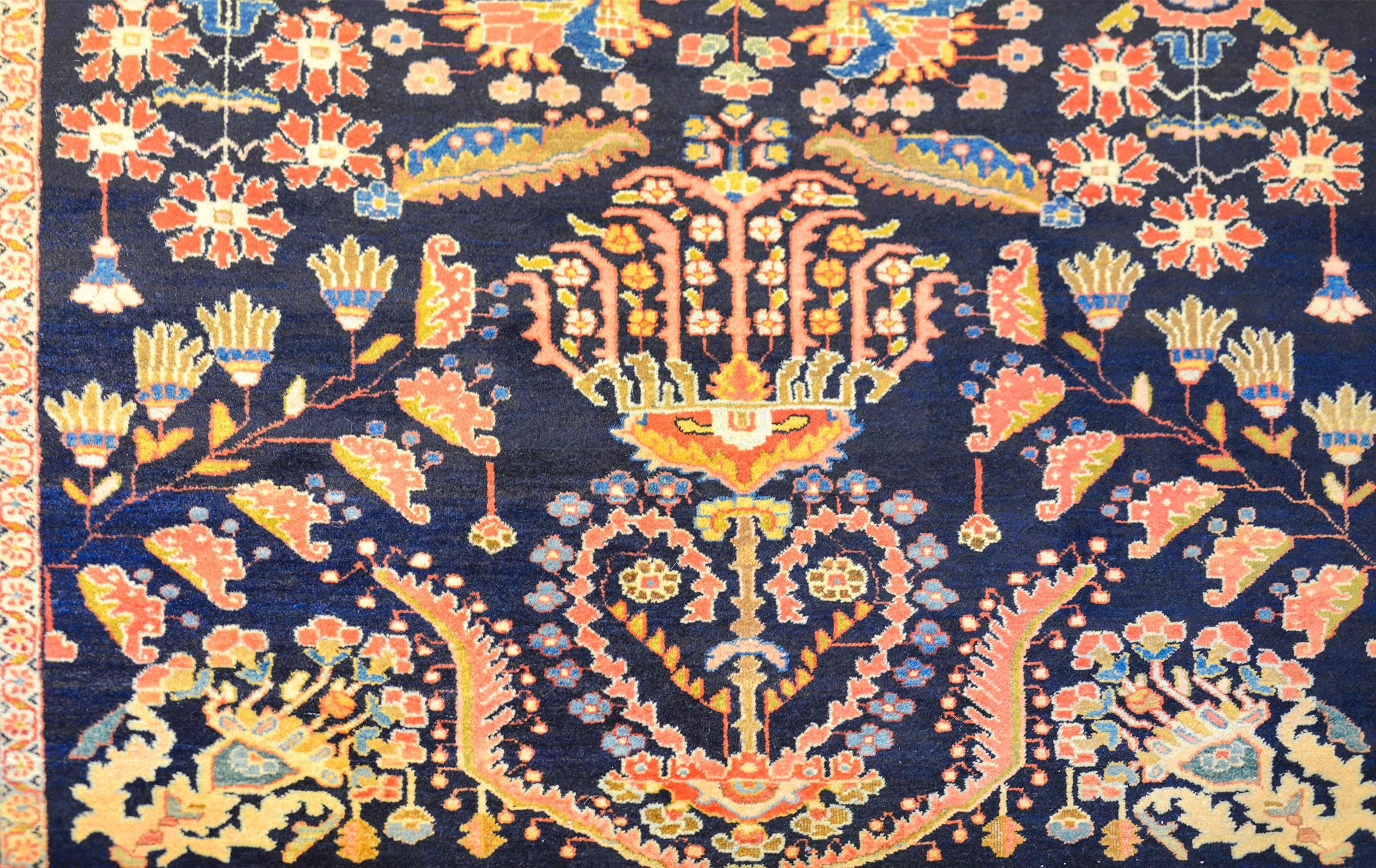 A fantastic 19th century Persian Mohajeran rug with a traditional mirrored tree-of-life and floral pattern woven in multicolored vegetable dyed wool on a dark indigo background. The border is contrasting with a floral and vine pattern woven in a