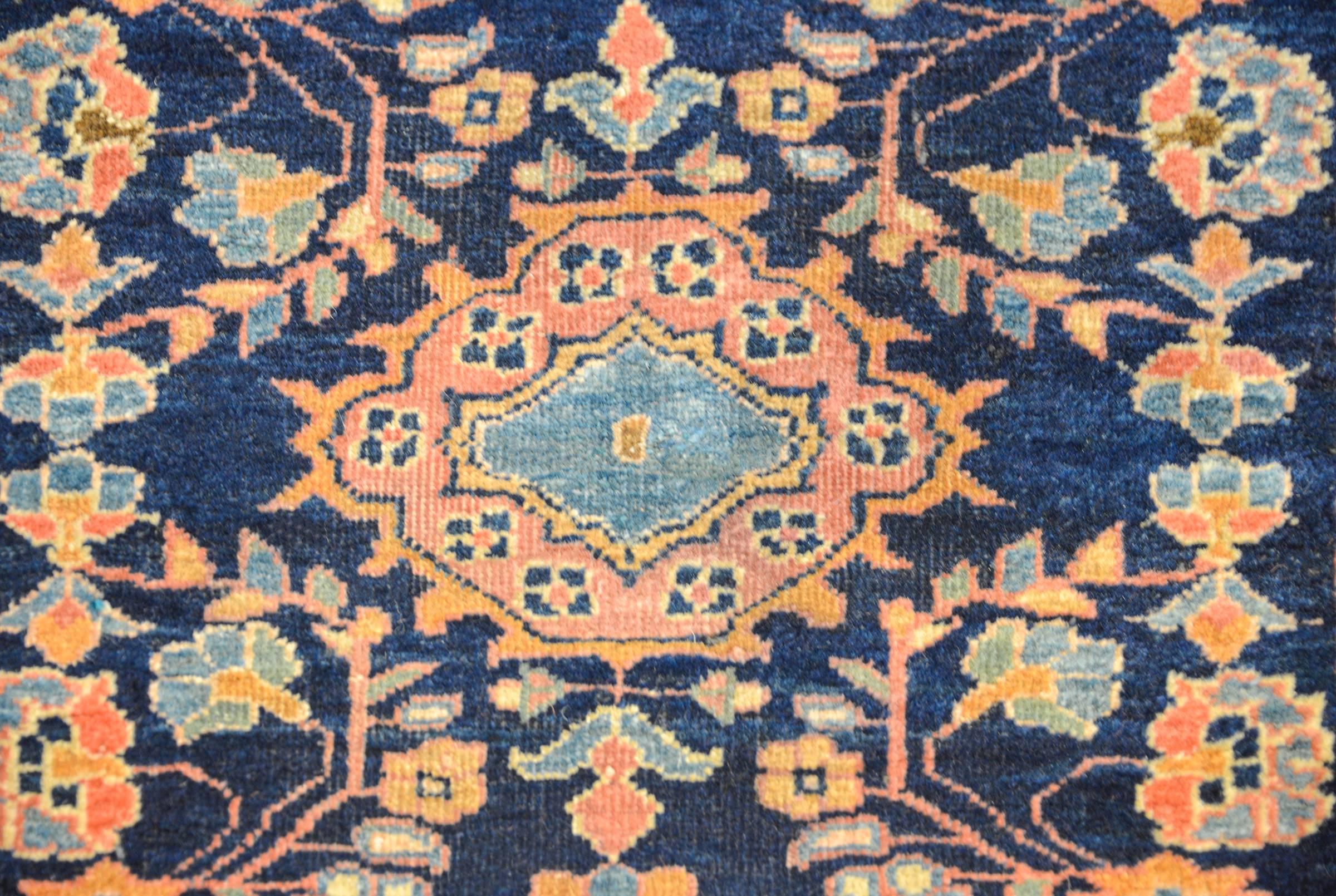 A fantastic 19th century Persian Sarouk Mohajeran rug with a traditional pattern consisting of a mirrored floral pattern woven in multicolored vegetable dyed wool on a dark indigo background. The border is complementary with a large-scale floral and