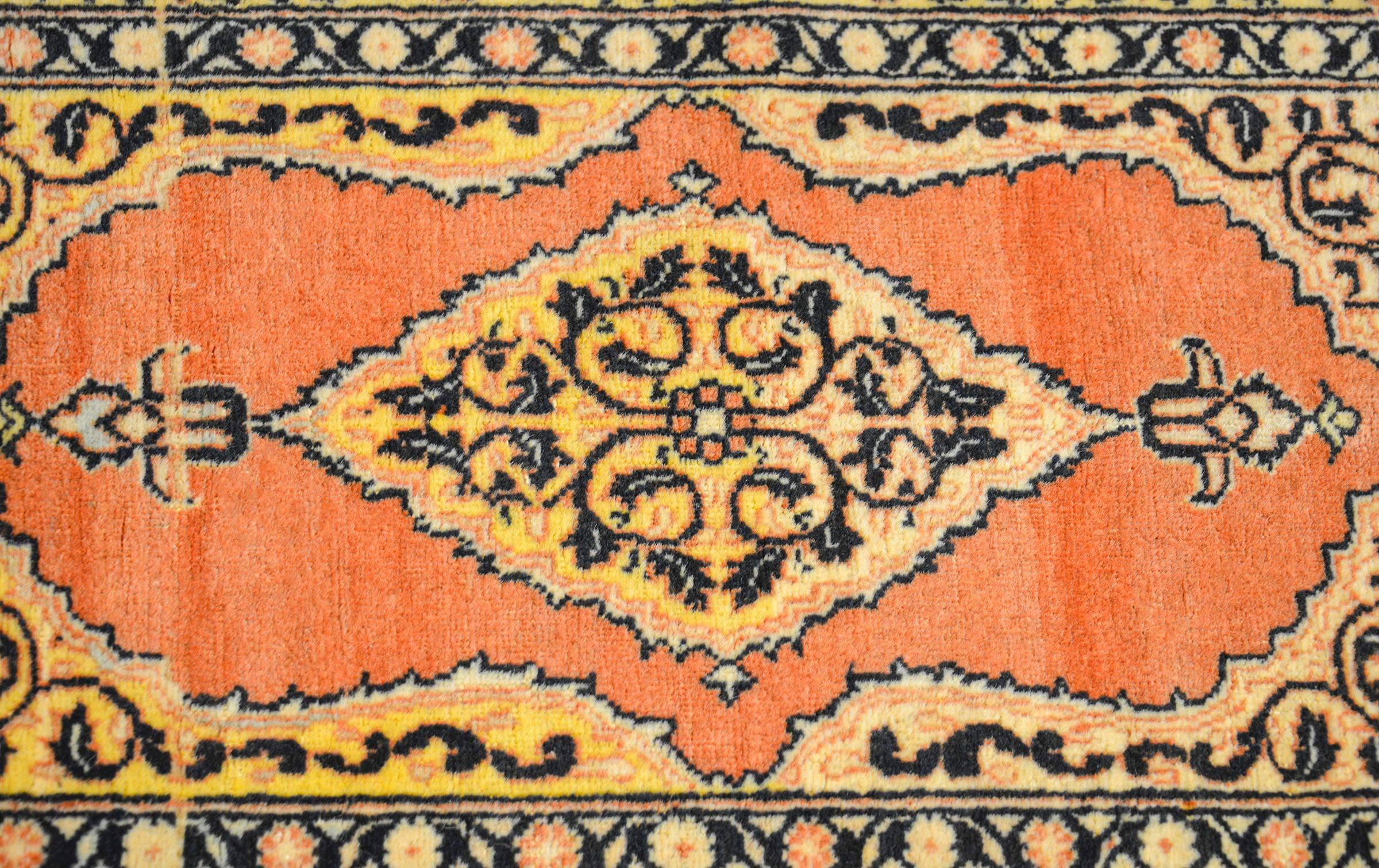 A 19th century Persian Tabriz rug of rare design with a doubt-lobed medallions woven in brash orange wool surrounded by an all-over floral and vine pattern woven in black and pink wool. The border blends in with the rest of the overall pattern.