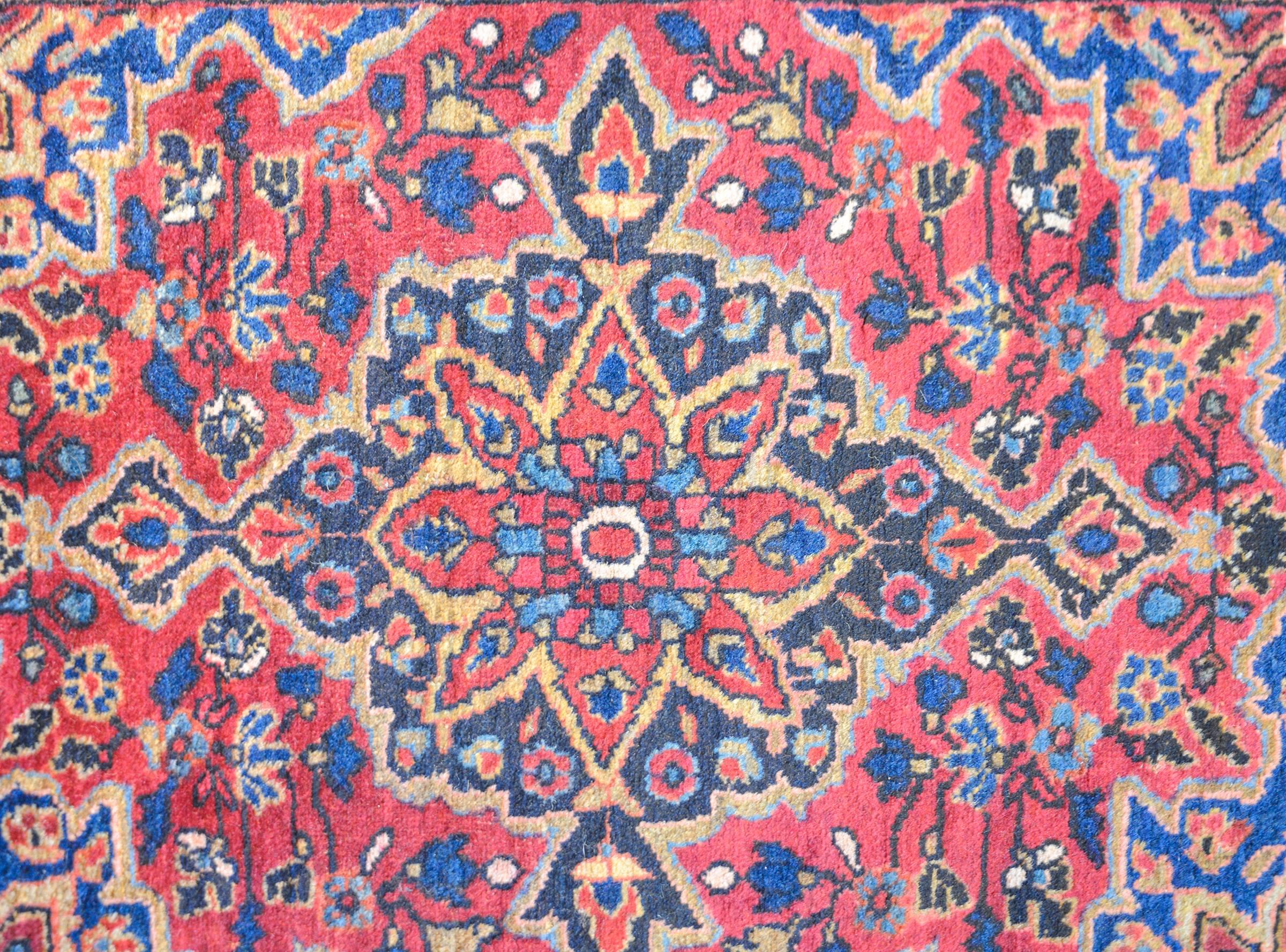 Ein ungewöhnlicher persischer Sarouk-Teppich aus dem frühen 20. Jahrhundert mit einem geometrischen Blumenmedaillon, das auf einem in hellem und dunklem Indigo, Gold und Preiselbeere gewebten Blumenfeld ruht. Die Bordüre ist mit einem großen Blumen-