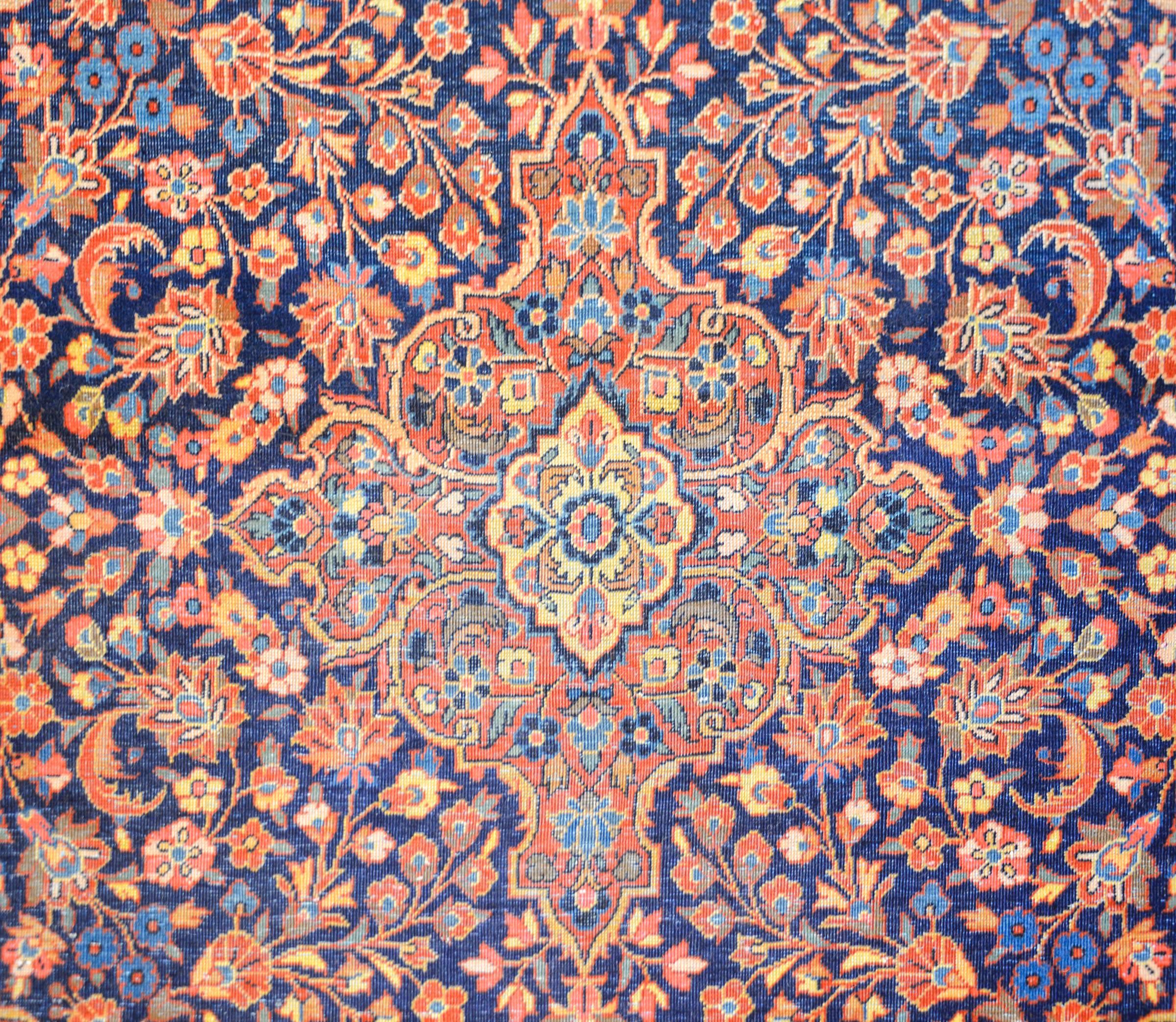 An unbelievable early 20th century Persian Kashan rug with an intense and densely woven all-over large and small-scale floral and vine patterns rendered in crimson, indigo and natural wool colors, all on a dark indigo background. The border is