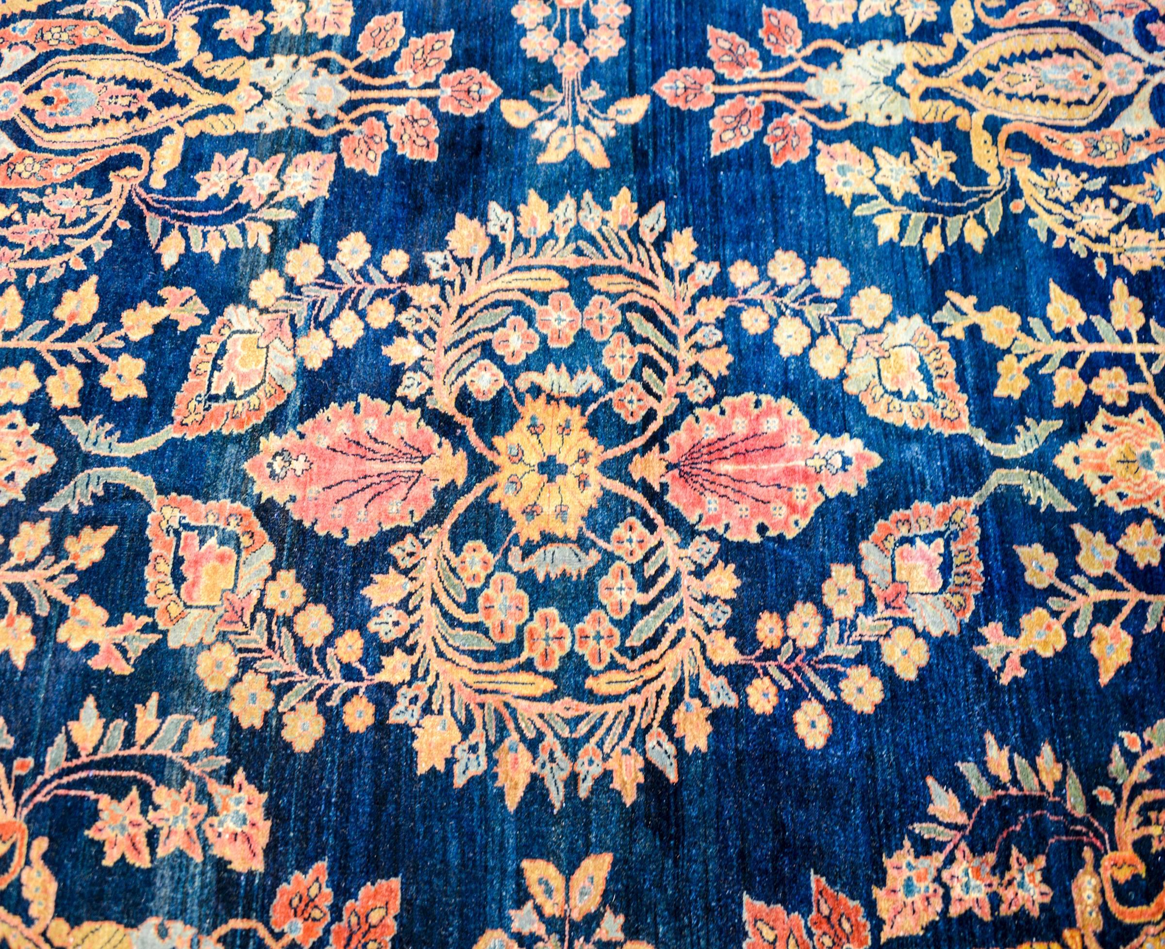 A remarkable Persian Sarouk Maharajan circa 1900 with an exquisite all-over mirrored floral and tree-of-life pattern woven in multicolored vegetable dyed wool on a natural indigo background. The border is complex with multiple wide and narrow