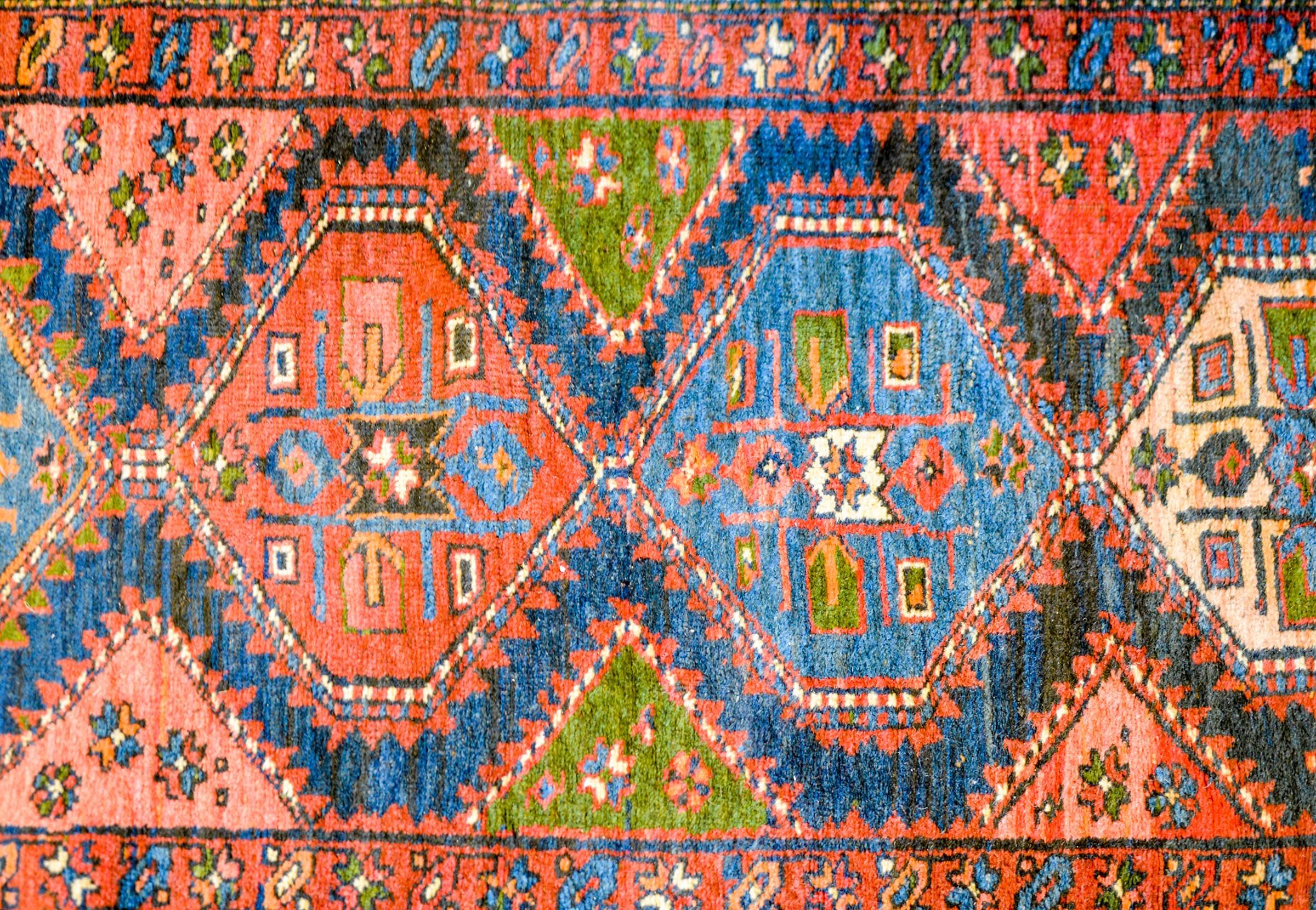 A wonderful early 20th century Persian Azari runner with multiple multicolored hexagonal medallions on an indigo background flanked with triangle-form fields of stylized flowers and animals. The border is comprised of three distinct patterns, the