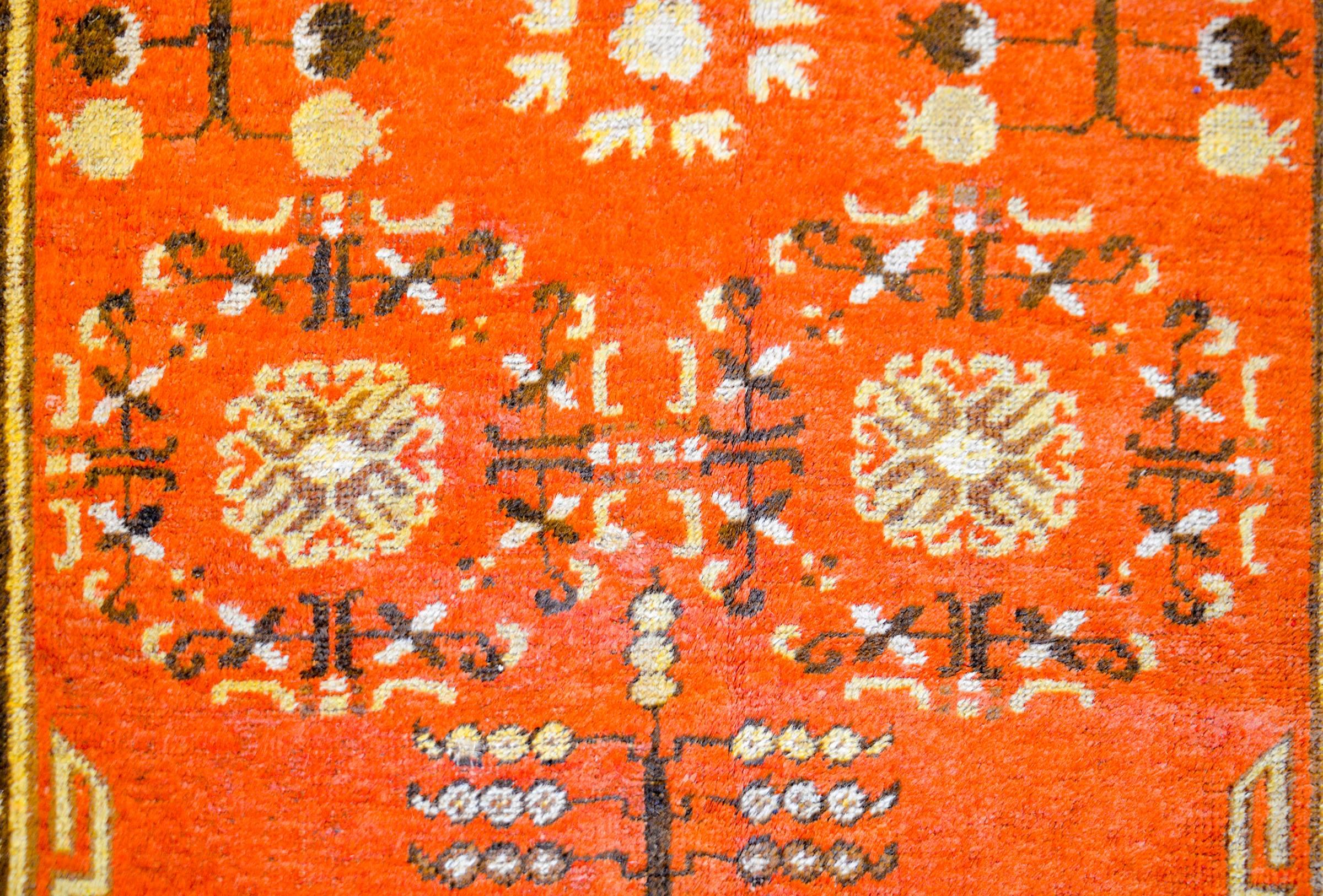 Alfombra Khotan de Asia Central de principios del siglo XX con un hermoso campo naranja de granadas, árboles de la vida y motivos florales. La cenefa está maravillosamente representada con motivos budistas de nudos interminables, nubes turbulentas y