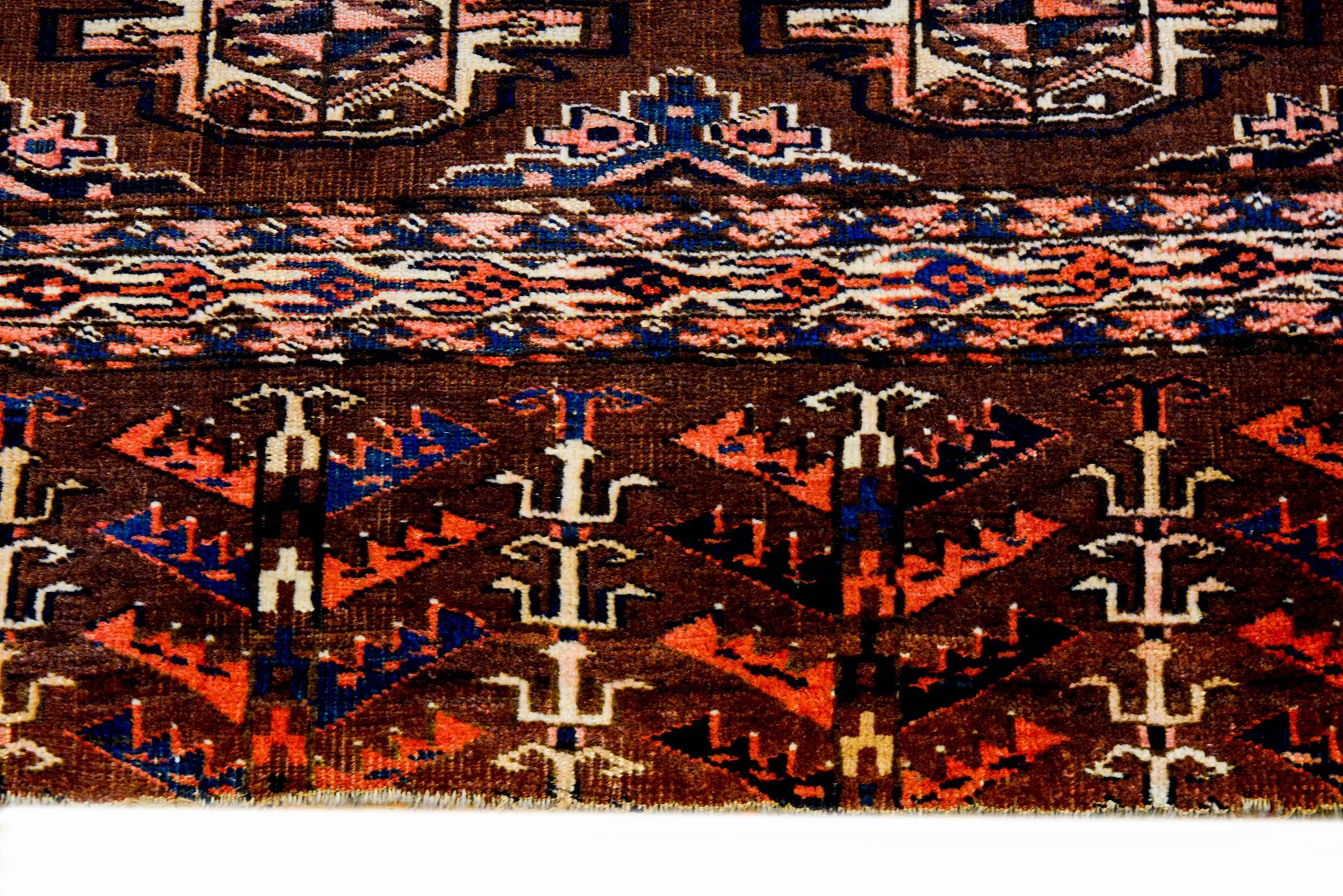 Ein wundervoller persischer Yamout-Teppich aus dem frühen 20. Jahrhundert mit einer asymmetrischen Komposition aus mehreren geometrischen Medaillons auf naturbraunem Wollgrund und einer breiten Bordüre mit stilisierten Blumen- und Blattmustern, die