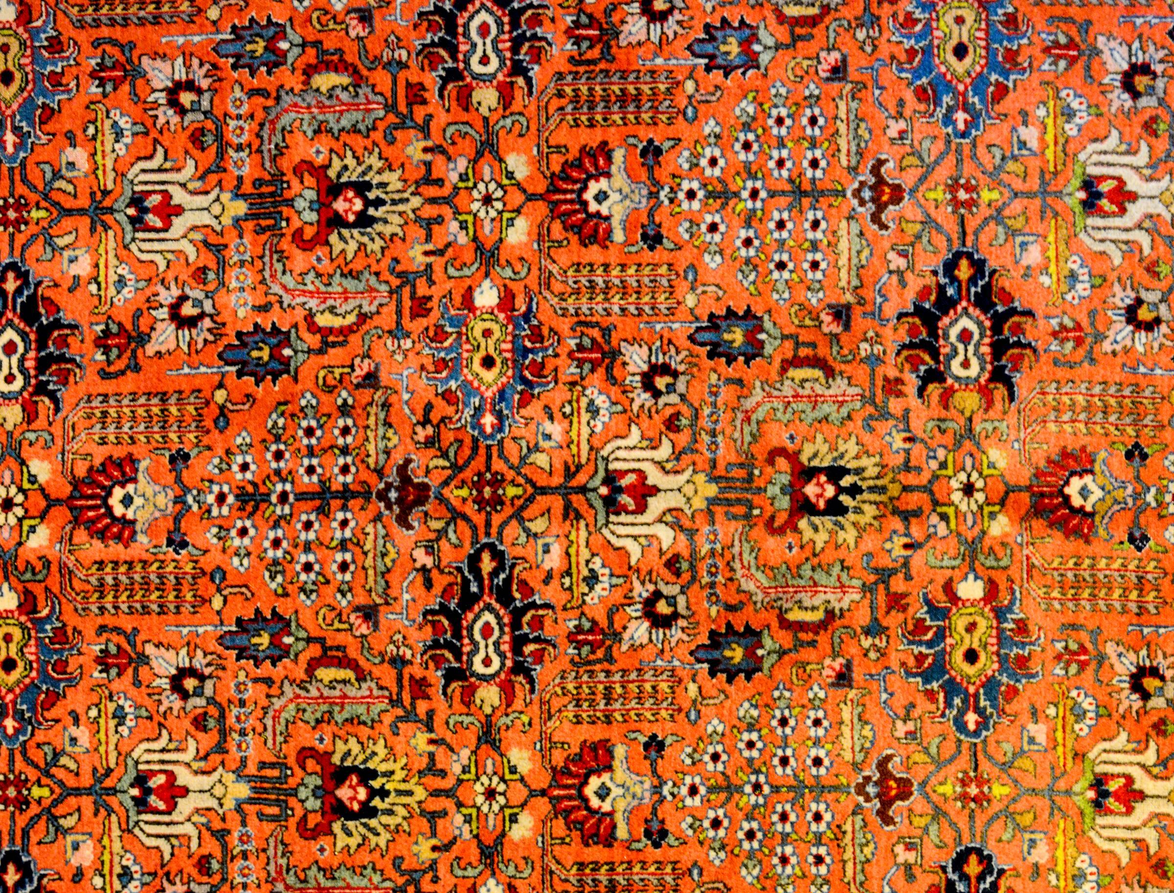 A wonderful early 20th century Persian Tabriz rug with an all-over mirrored floral pattern woven in crimson, indigo, gold and green, on an amazing flame-orange background. The border is exceptional with a large-scale multicolored floral and leaf