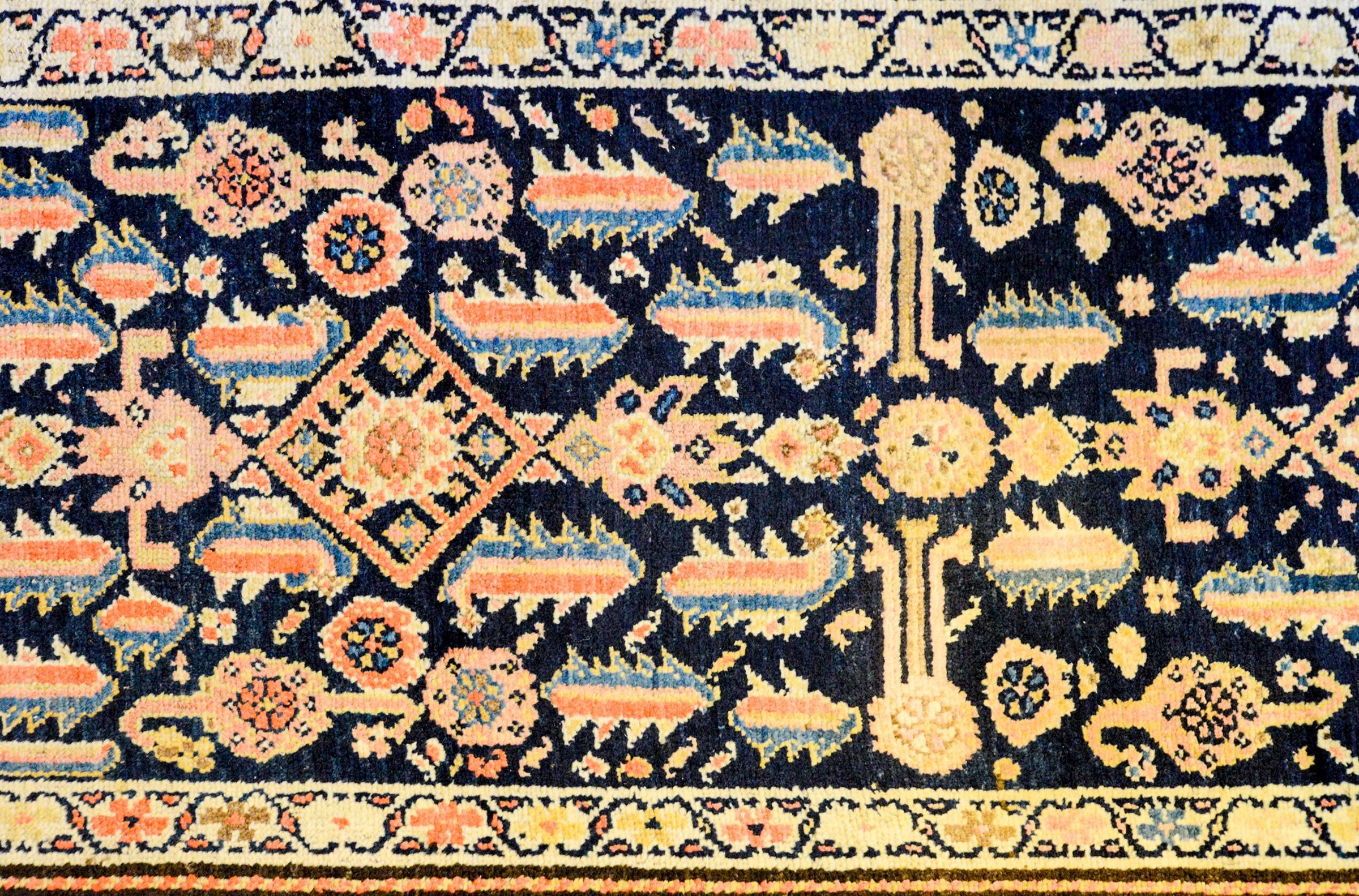 An early 20th century Kurdish runner with a beautiful all-over pattern of multicolored shrimp and flowers on a dark indigo background. The border is wide, with a large-scale paisley pattern on a yellow background, flanked by two contrasting petite