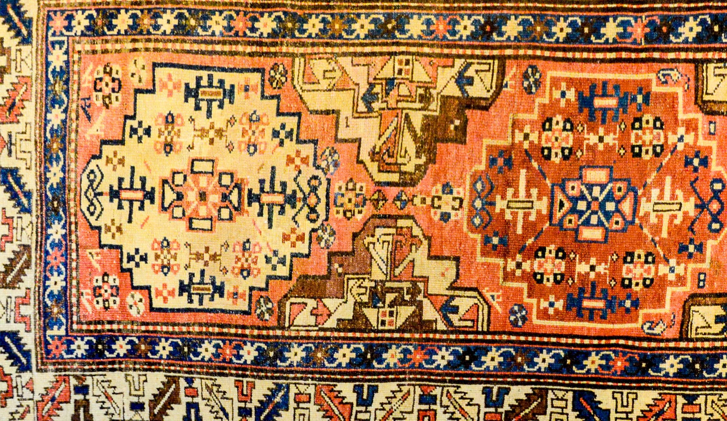 An incredible circa 1900 North West Persian runner with three beautiful geometric medallions, one crimson, one indigo, and one pale cream, each woven with geometric flowers, all on a pale orange background. The border is complex with three distinct