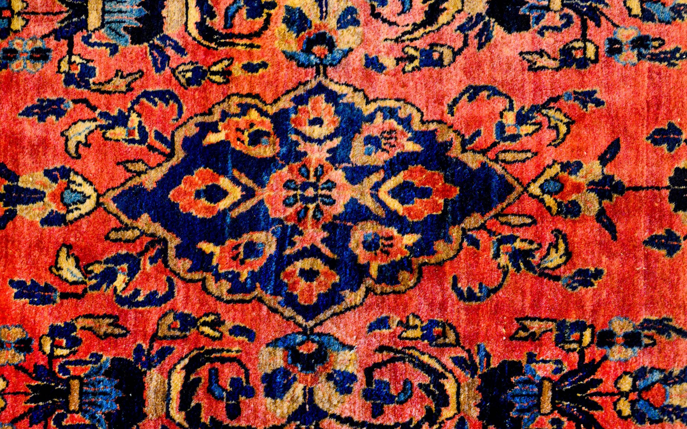 An exceptional early 20th century Persian Sarouk Mohajeran Runner with a beautiful mirrored floral and vine pattern woven in light and dark indigo, and cream colored wool, on a beautiful rich coral background. The border is wonderfully rendered with