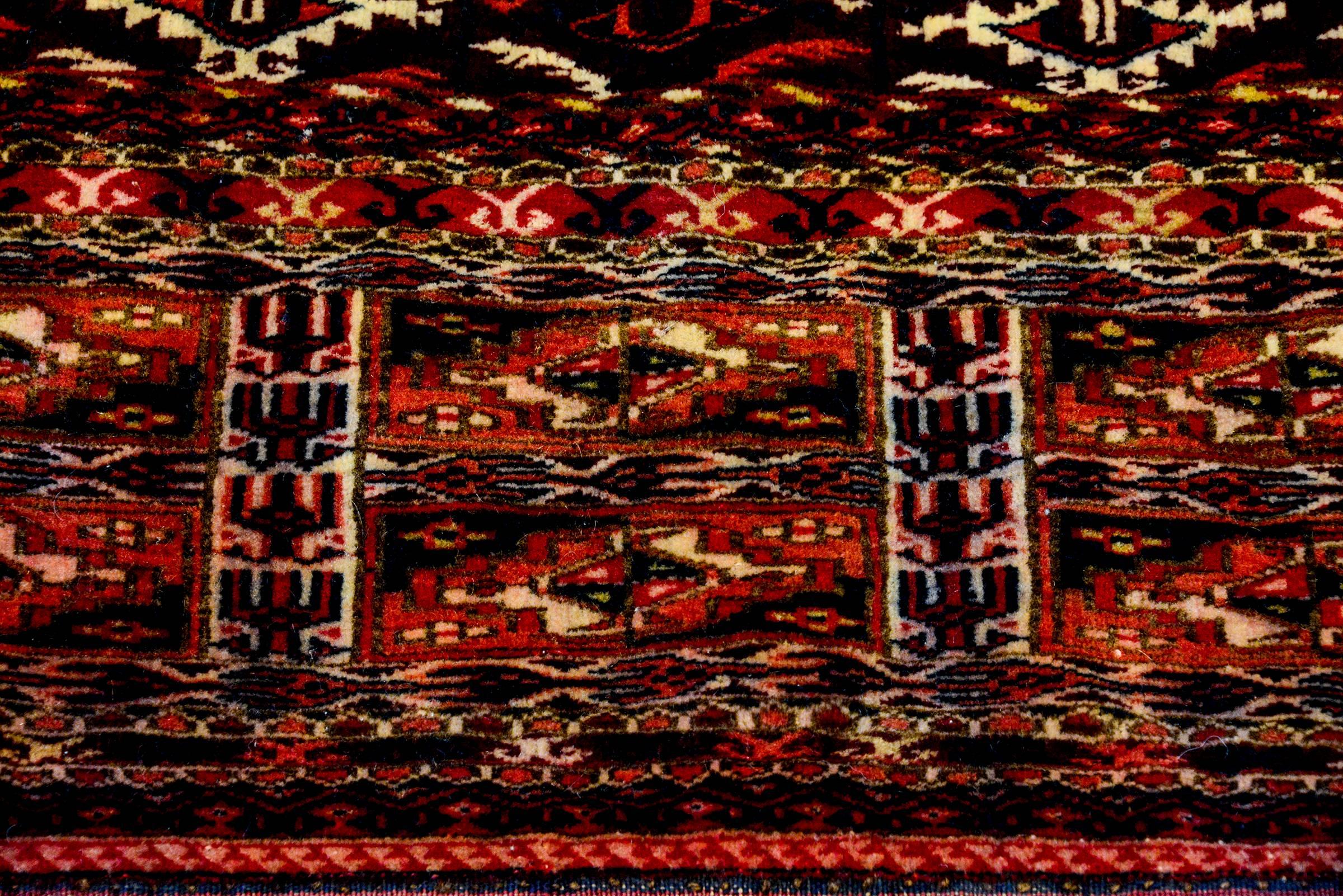A wonderful early 20th century Persian Turkmen face rug with a densely woven geometric pattern woven in crimson and indigo and natural wool, with a wide complimentary geometric border. One side has long multicolored fringe.