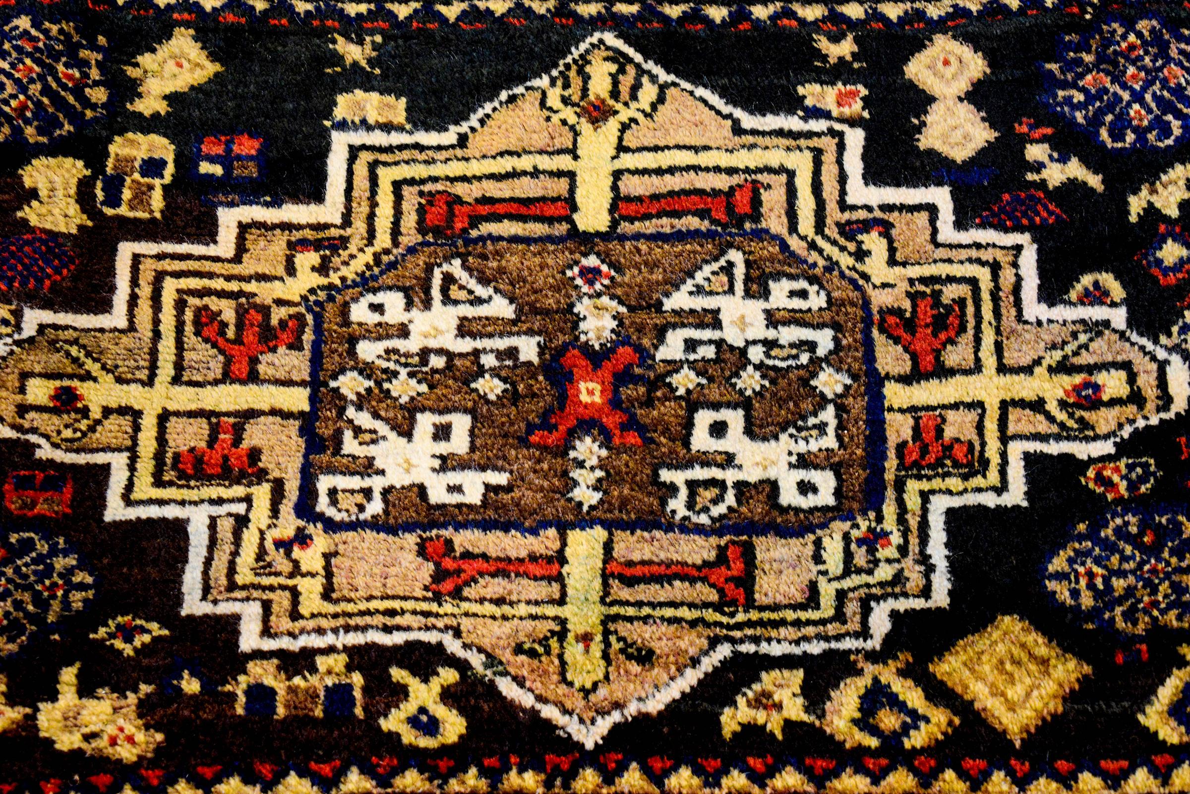 A wonderful petite early 20th century Persian Azeri rug with a large central geometric medallion woven in crimson, gold, and cream and brown undyed wool. The medallion lives amidst a field of geometric designed flowers, on a brown, undyed wool,