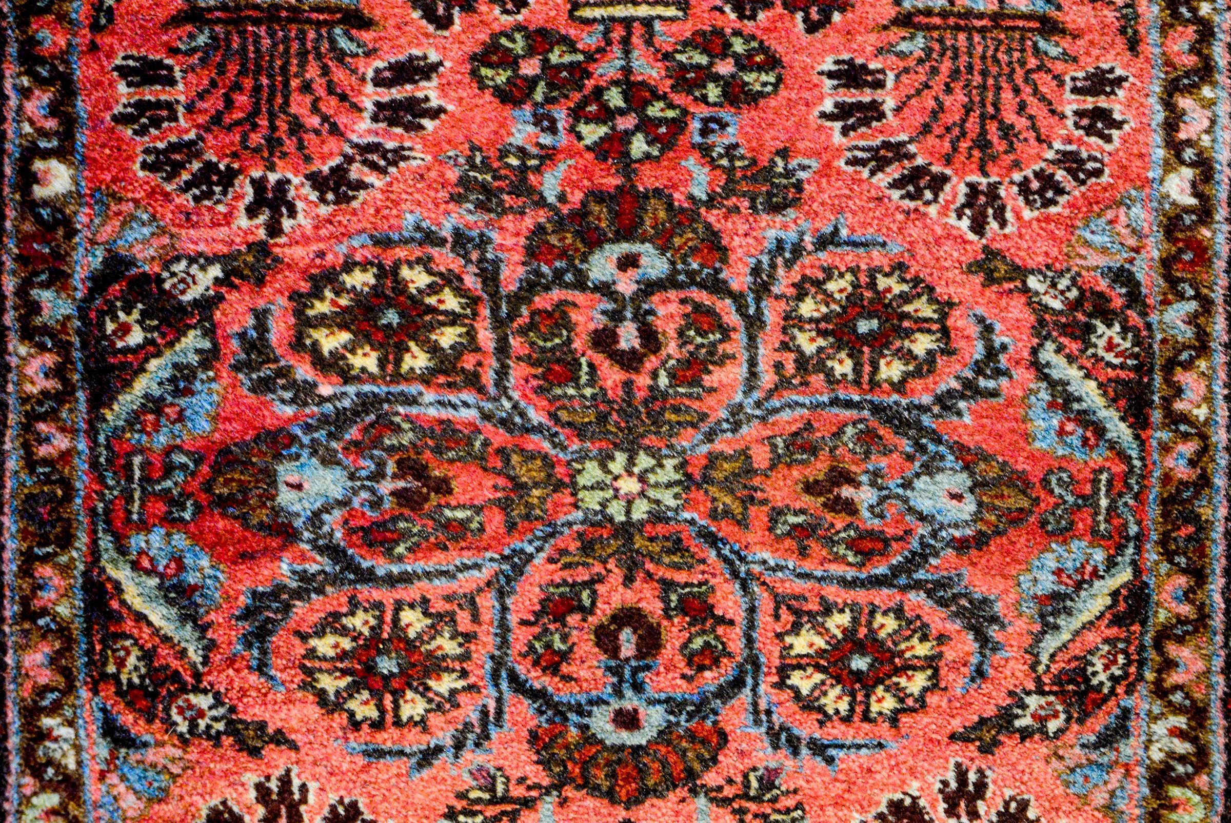 An exceptional early 20th Century Petite Lilihan rug with a traditional mirrored floral pattern woven in light and dark indigo and natural wool on a coral background. The border is complex with three distinct floral and vine patterns on a brown