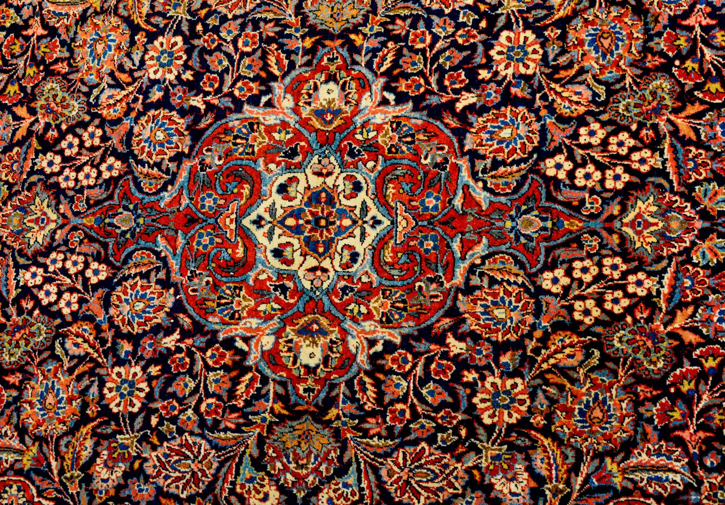 An unbelievable early 20th century Persian Kashan rug with the most densely woven field of myriad flowers, leaves, and vines, all woven in crimson, indigo, gold, and cream colored vegetable dyed wool. The border is as decency woven as the field,