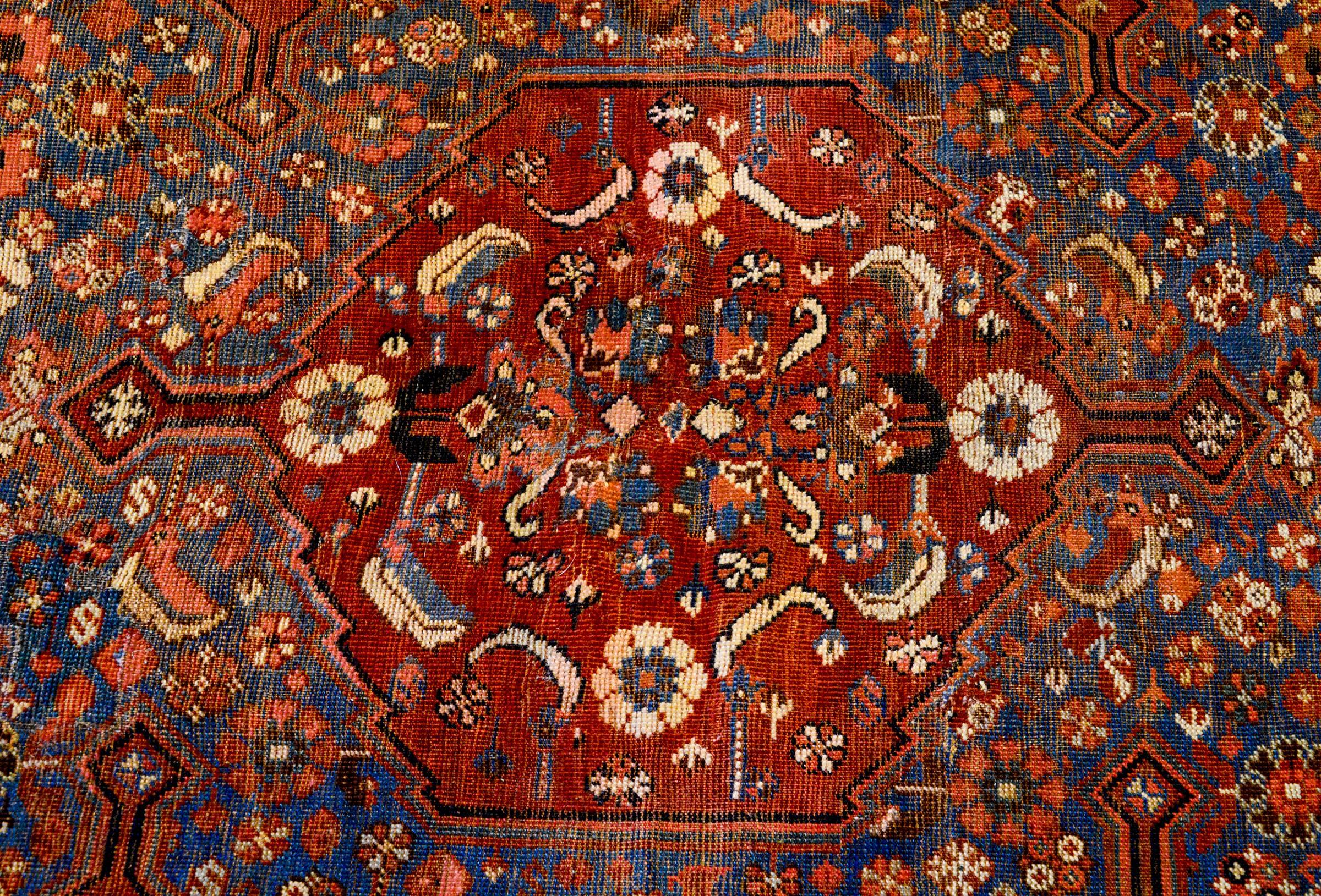 An outstanding, really fine, 19th century Persian Qashqai rug with an incredible pattern containing a large crimson medallion filled with leaves and flowers, amidst a field of myriad flowers, on a beautiful abrash indigo background. The border is