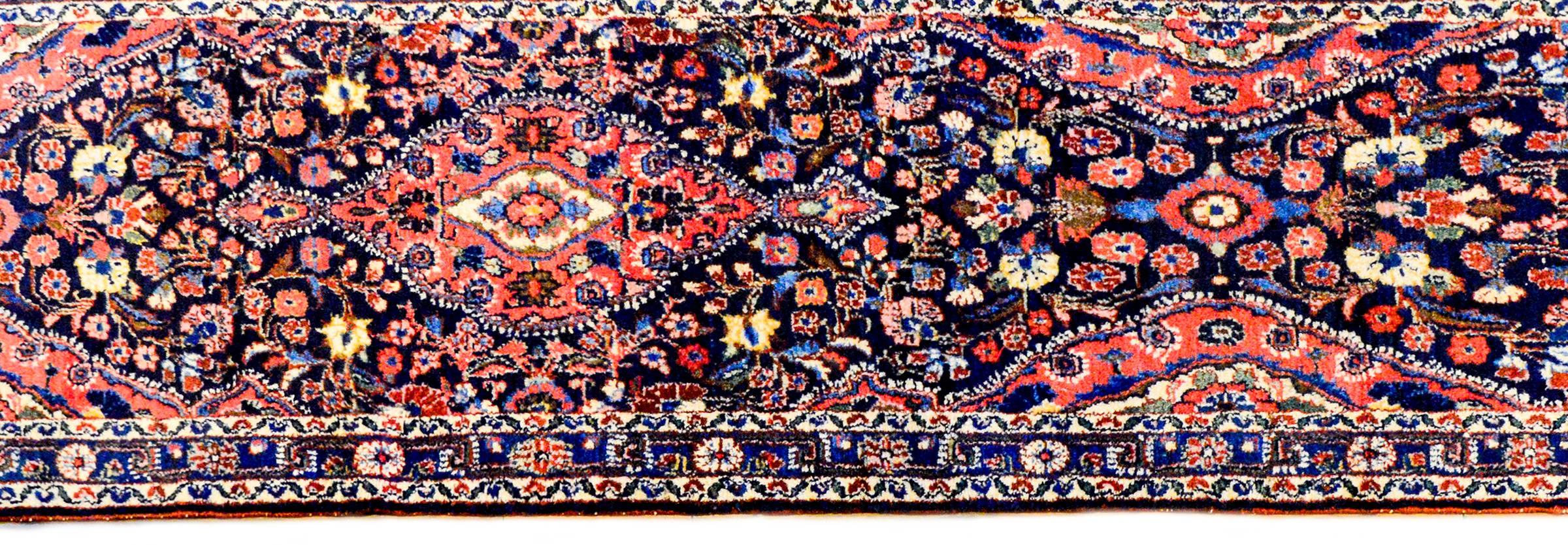 An exceptional early 20th century Persian Lilihan runner with an incredibly woven field of flowers, woven in crimson, light and dark indigo, and natural undyed cream colored wool, on a black background. The border is narrow, with a central floral