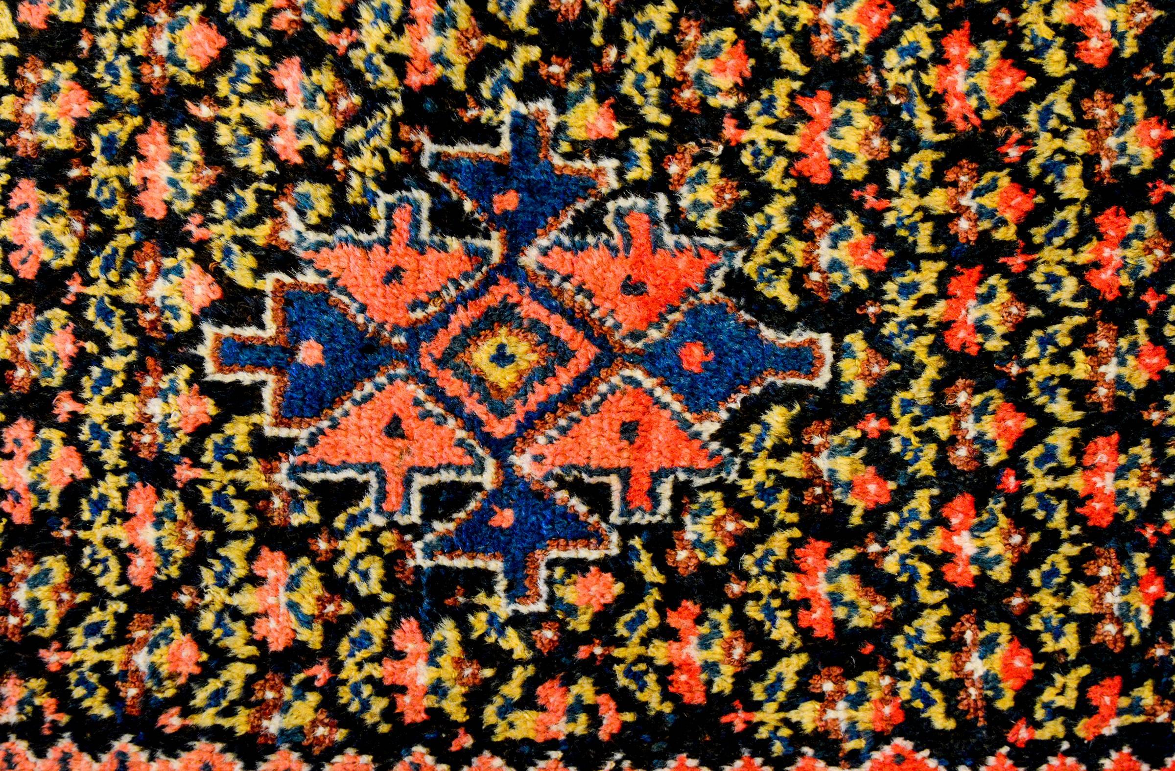 An early 20th century Persian Turkmen rug with a beautiful multi-colors petite floral patterned background, with a central crimson and indigo medallion composed of eight arrows. The border is complex, composed of seven distinct patterns, two with a