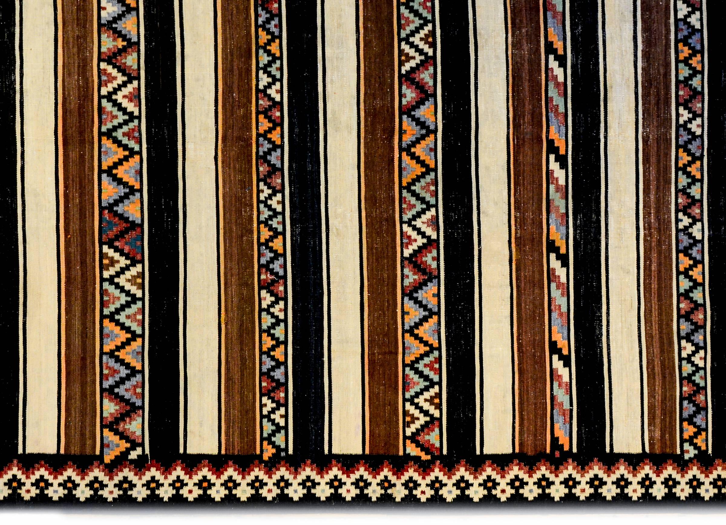 A fantastic mid-20th century Shahseven Kilim runner with a pattern comprised of alternating solid black, cream, and brown, natural undyed wool stripes, and multiple zigzag and diagonal stripes, woven in crimson, indigo, gold, green and black natural