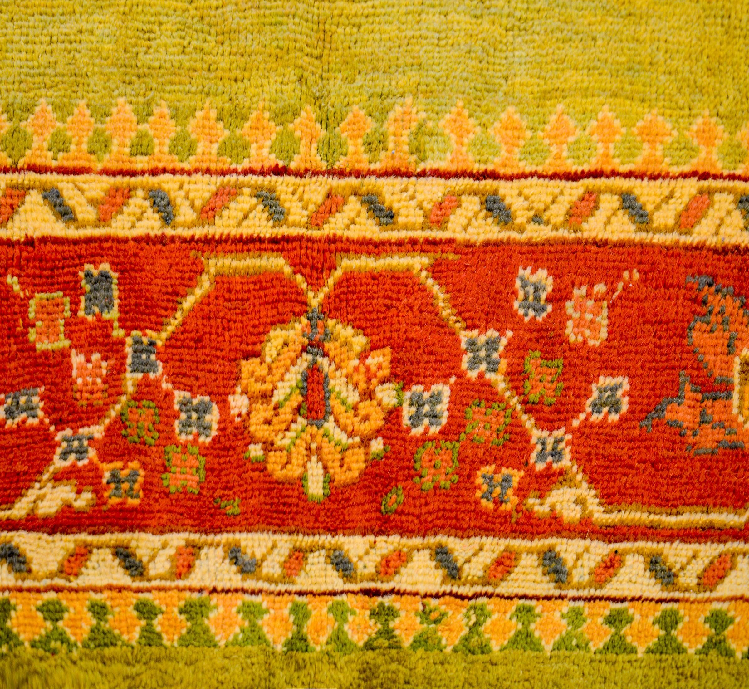 A wonderful early 20th century Turkish Oushak rug with an incredible brilliant pea green vegetable dyed wool field, surrounded by a wide crimson border with an amazing large-scale floral and vine pattern flanked by two thin geometric borders.
