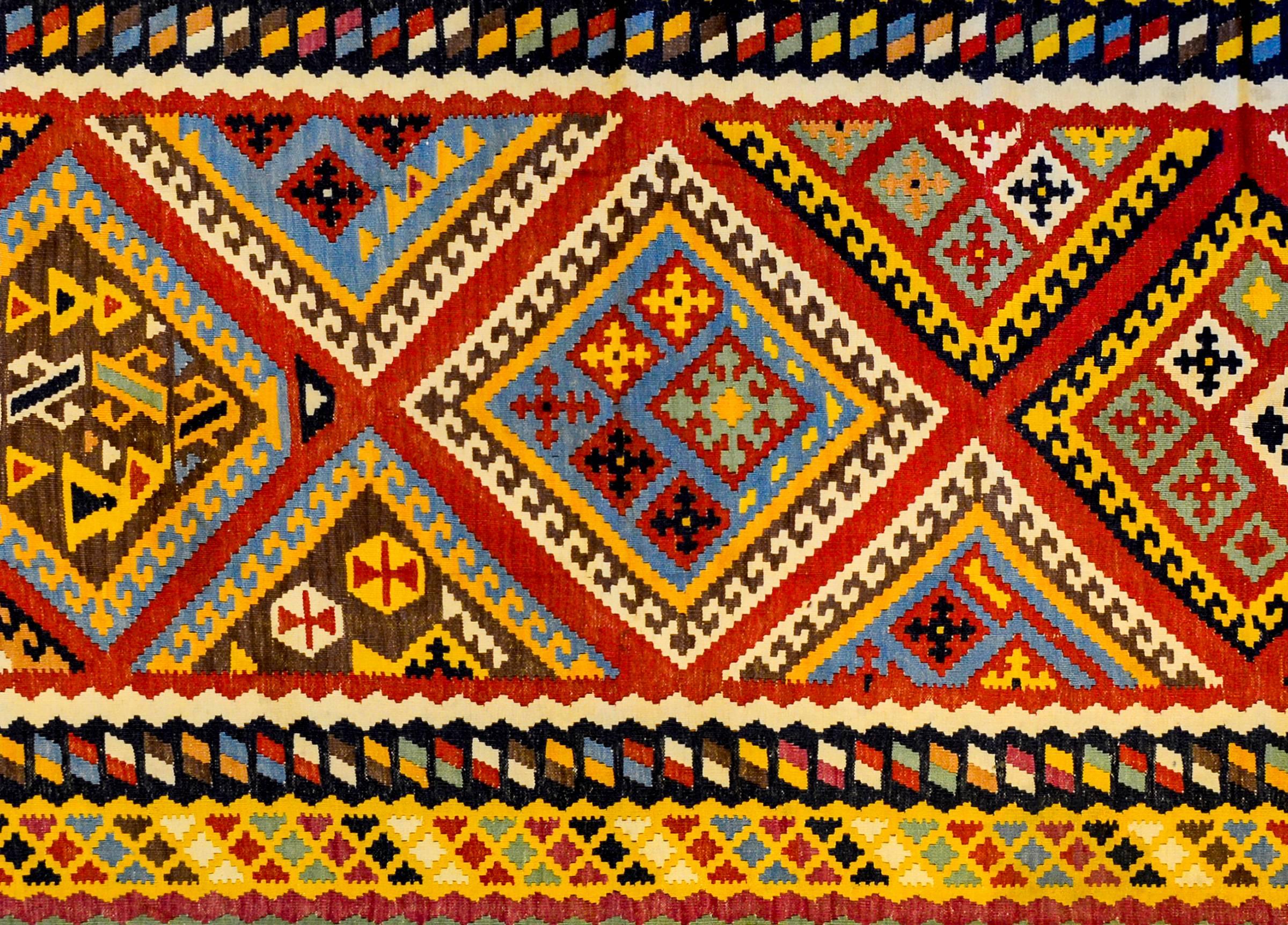 An outstanding mid-20th century Shiraz Kilim runner with an incredibly woven pattern containing stylized geometric flowers on diamond medallions, all woven in crimson, indigo, gold, green, and natural undyed brown and cream wool. The border is