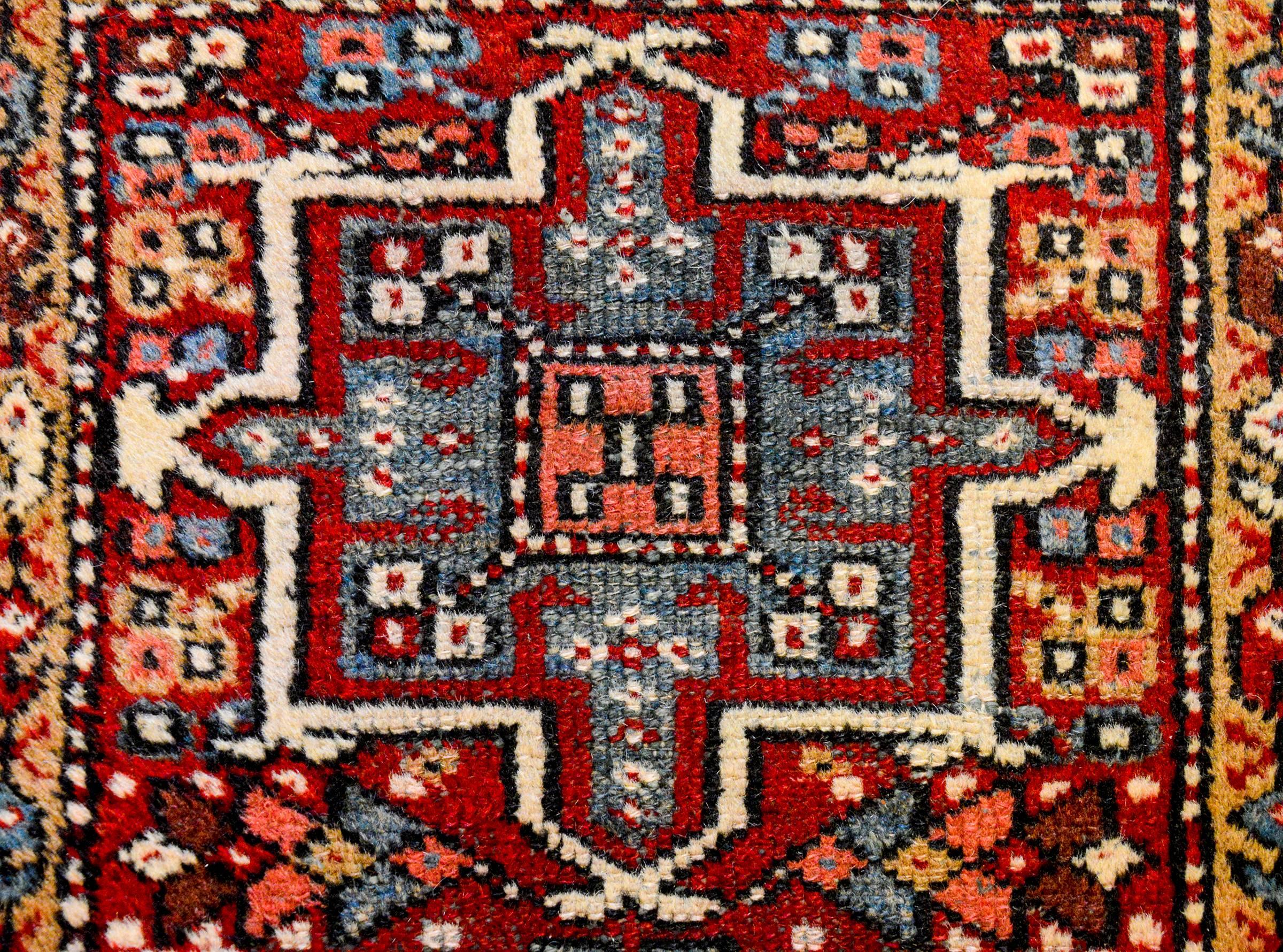 A wonderful early 20th century Northwest Persian runner with four large-scale medallions, woven in indigo and crimson amidst a field of flowers on a crimson background. The border is beautiful, with a multicolored paisley pattern.