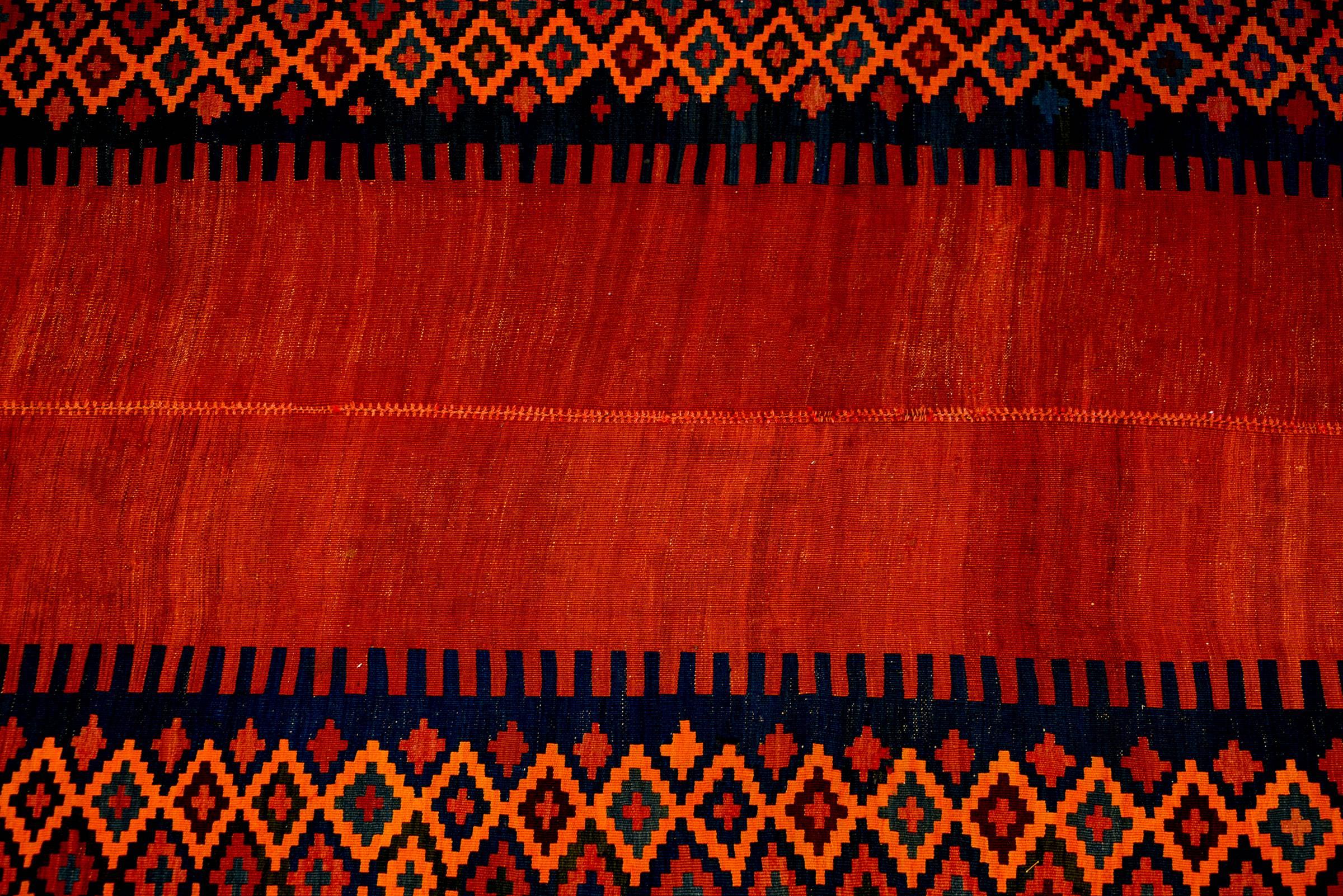 An amazing mid-20th century Kurdish Kilim runner with a fantastic abrash crimson field surrounded by a wonderful diamond pattern border. An interesting contemporary twist emerges as this rug has been cut in half and re-woven with one side flipped