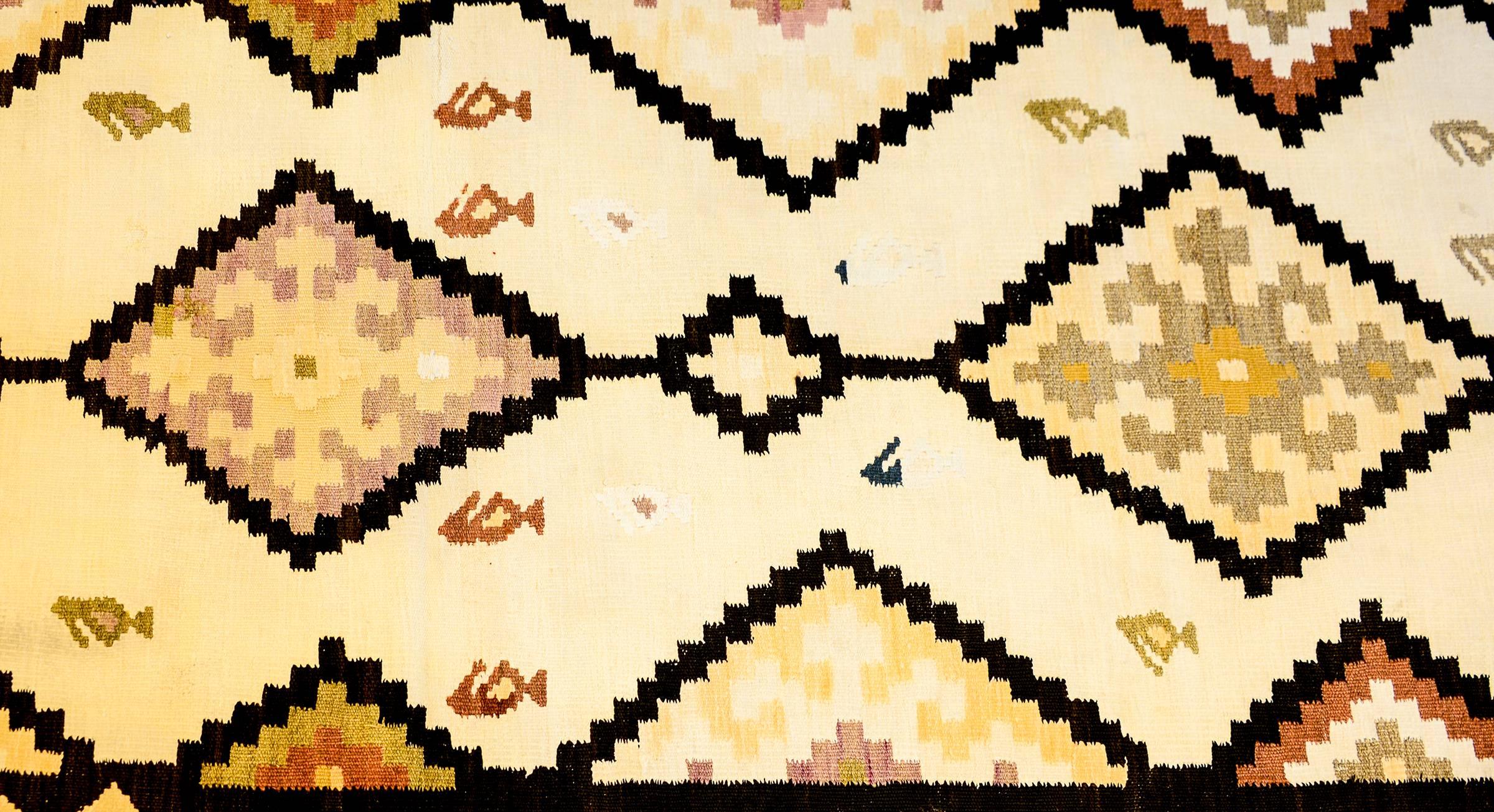 A wonderful early 20th century Persian Kilim runner with a fantastic geometric pattern containing multiple diamond form medallions and triangles, with a beautiful cream colored ground dotted with paisleys. The borer is complementary woven in similar