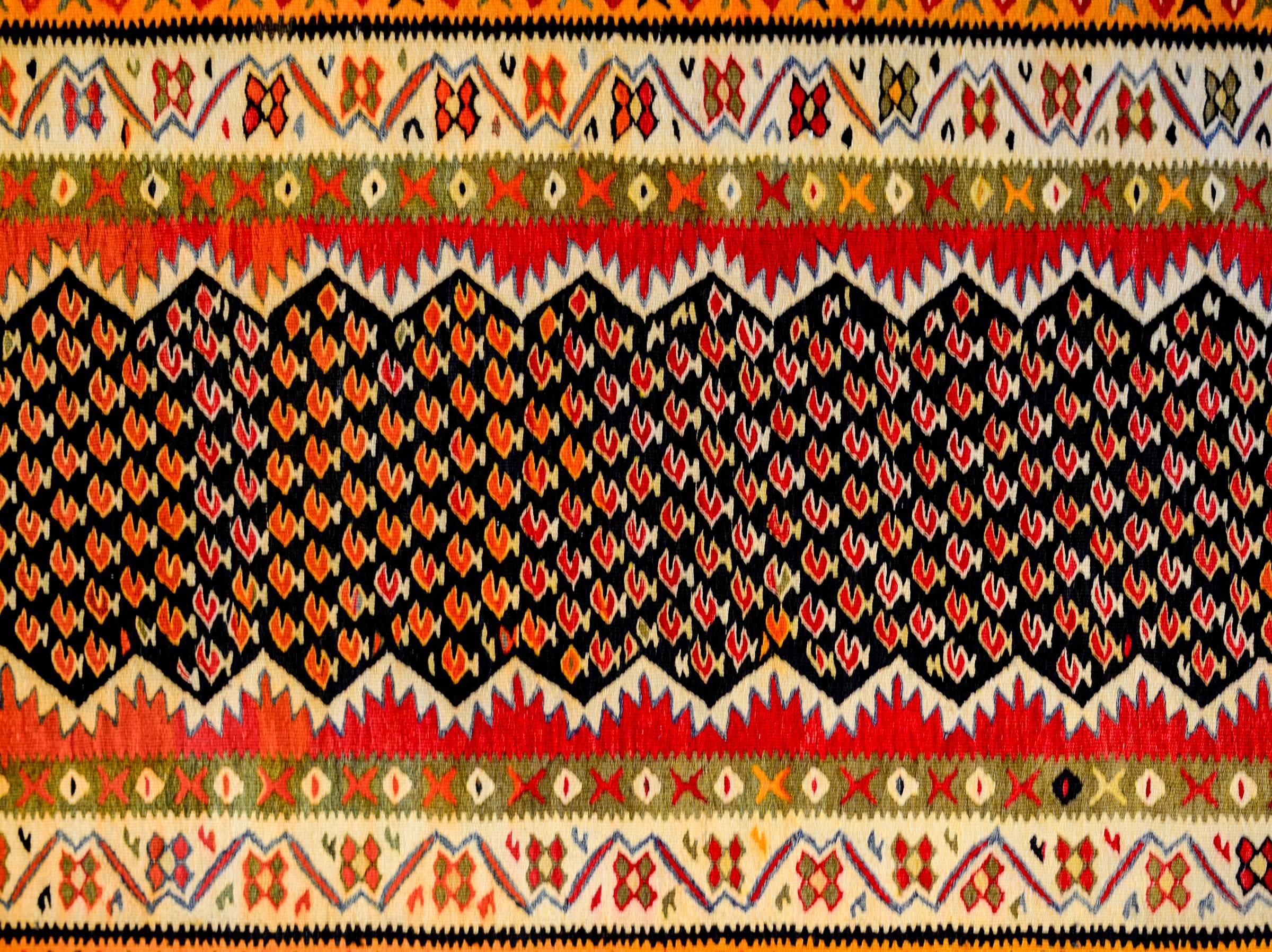 Ein wundervoller persisch-kurdischer Kelim-Läufer aus der Mitte des 20. Jahrhunderts mit einem karmesinroten Paisleymuster auf schwarzem Grund, umgeben von einer komplexen Bordüre aus fünf verschiedenen floralen und geometrischen Mustern, gewebt aus