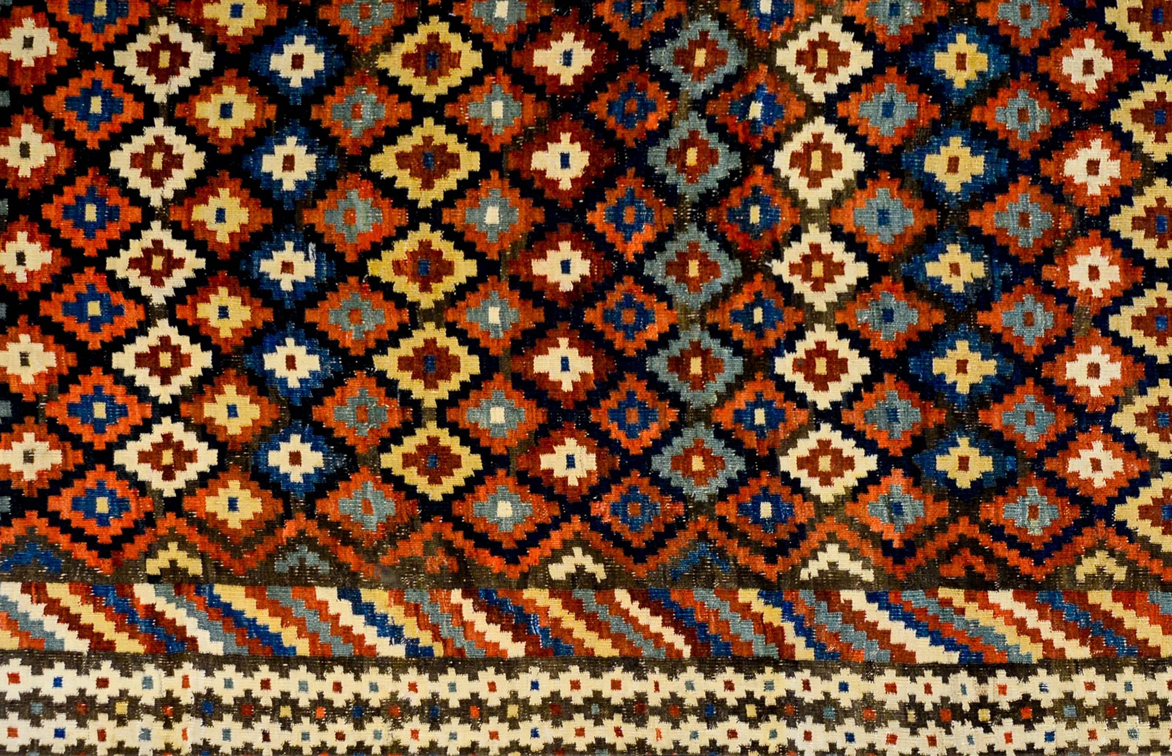 A wonderful early 20th century Shahsavan Kilim runner with a traditional multicolored crimson, sage green, indigo, and natural colored wool diamond pattern composed in a striped pattern running across the field. The border is wide with a