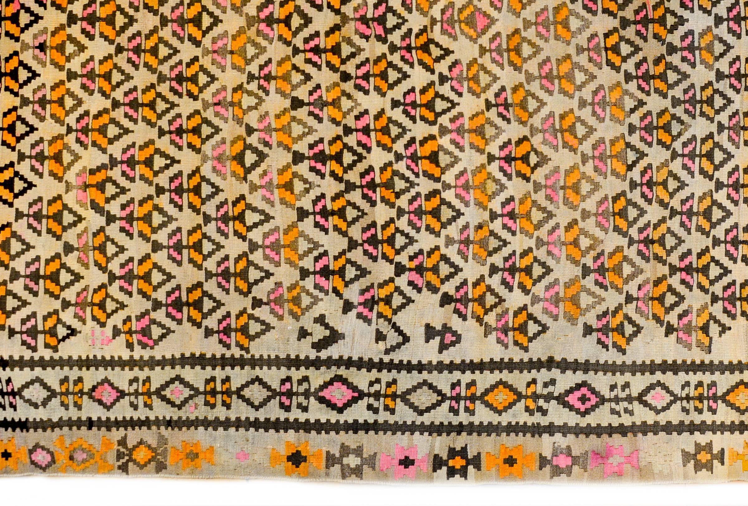 An exceptional early 20th century Persian Qazvin Kilim runner with a wonderful all-over multicolored stylized tree-of-life pattern across the field woven in black and orange vegetable dyed wool on a natural cream colored wool background. The border