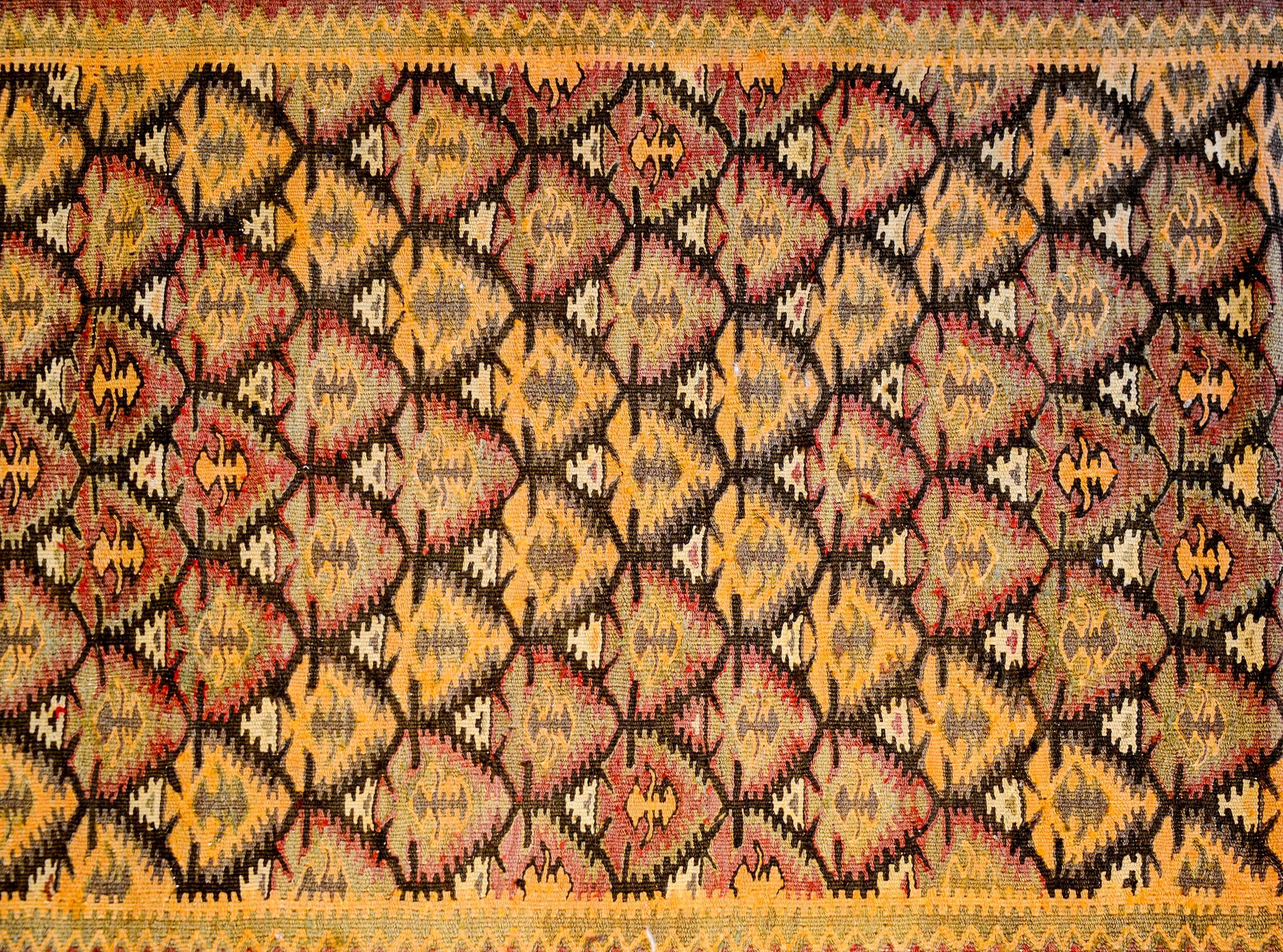 A Classic early 20th century Persian Qazvin Kilim runner with an all-over orange, purple, black and white tree-of-life pattern surrounded by multiple geometric patterned border. The central border is white with multicolored stylized flowers, flanked