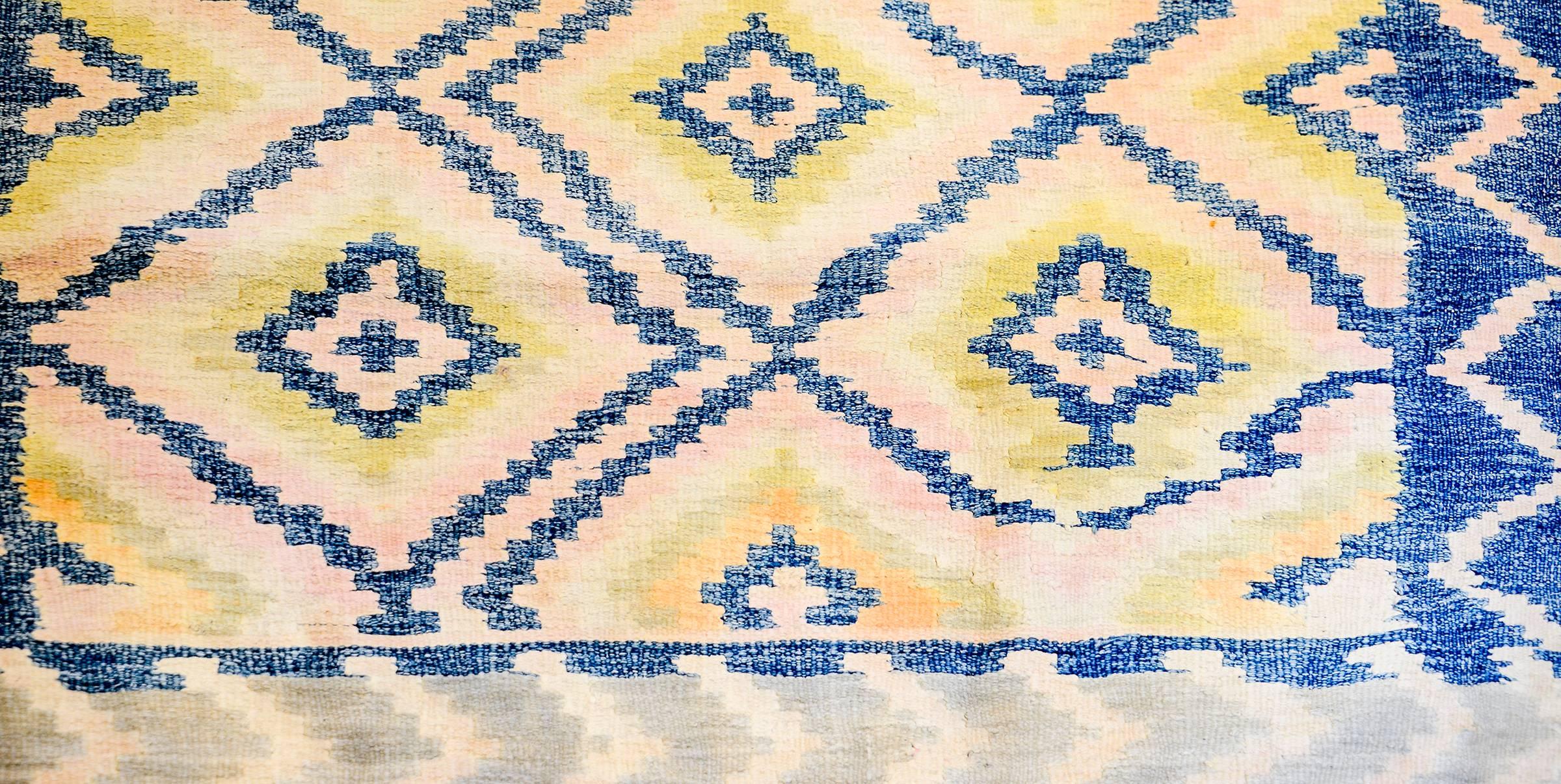 An amazing early 20th century Persian Saveh iilim runner with an all-over indigo diamond pattern on a pale yellow, green and pink background. The border is wide with a similarly colored zigzag pattern.