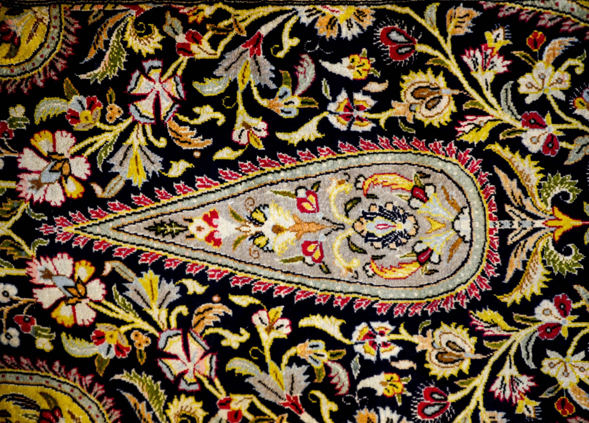 A wonderful late 20th century Persian Qum runner with four tear-drop shaped medallions amidst a wonderful field of scrolling vines and flowers on an abrash indigo background. The border is sweet and a wide floral and vines stripe on a cream