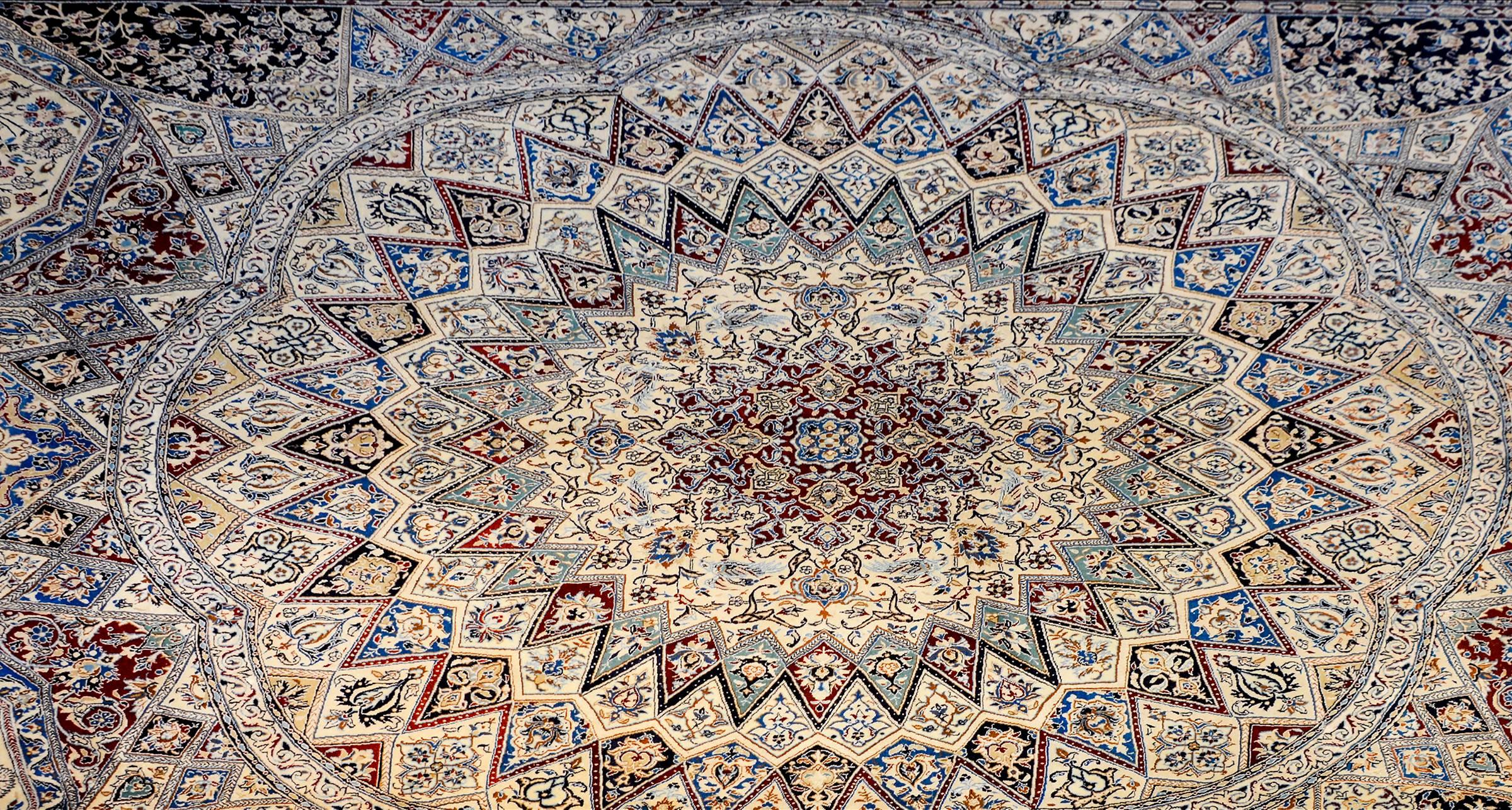 A mesmerizing Vintage Persian Nain rug with a fantastic medallion radiating with floral and vine, and geometric rays amidst a field of flowers, all woven in light and dark indigo, crimson and natural undyed wool. The border is wide, with multiple