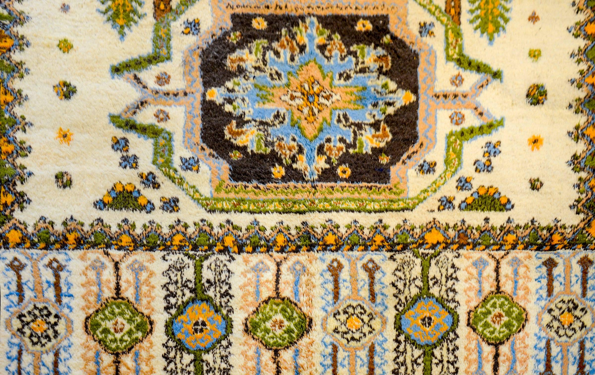 A beautiful, circa 1990s Moroccan rug with a fantastic pattern containing three large geometric and floral form medallions woven in light and dark green, gold, and indigo vegetable dyed wool on a natural undyed wool background. The border is wide,