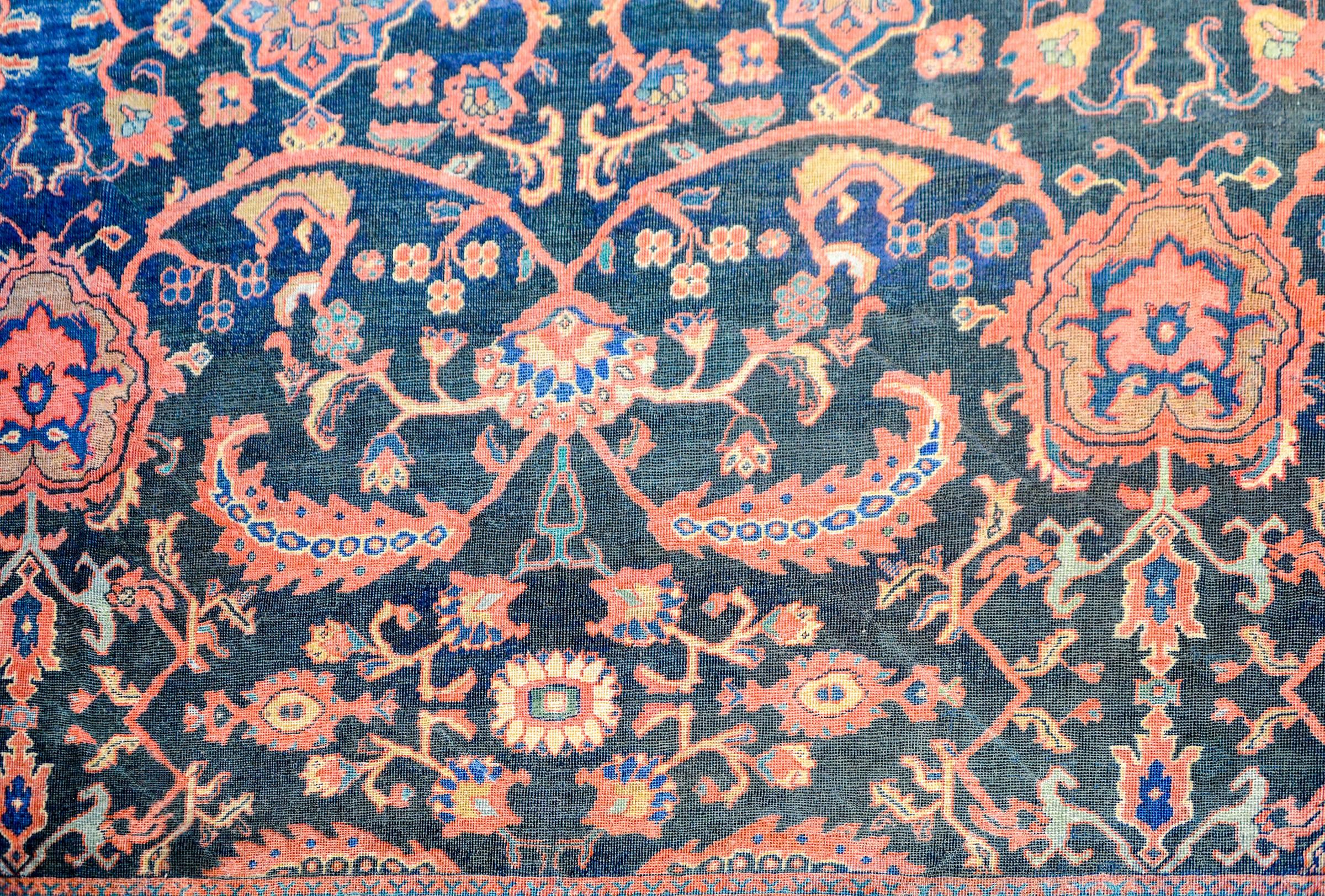 An extraordinary early 20th century Persian Mahal rug with an amazing all-over pattern of multicolored flowers in a wonderful lattice pattern on an indigo background. The wide border is composed with scrolling vines criss-crossing a garden of