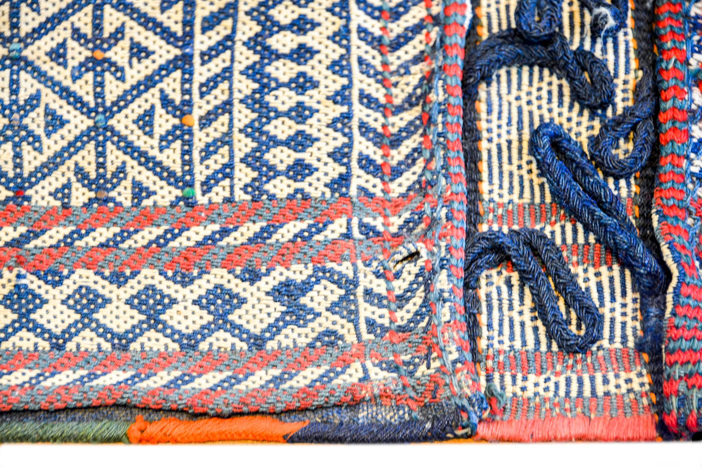 A fantastic early 20th century Persian Bakhtiari saddle bag with a beautiful woven geometric pattern woven in indigo and white wool, flanked by a border of red and green, and blue and white stripes. The corners are covered in leather.