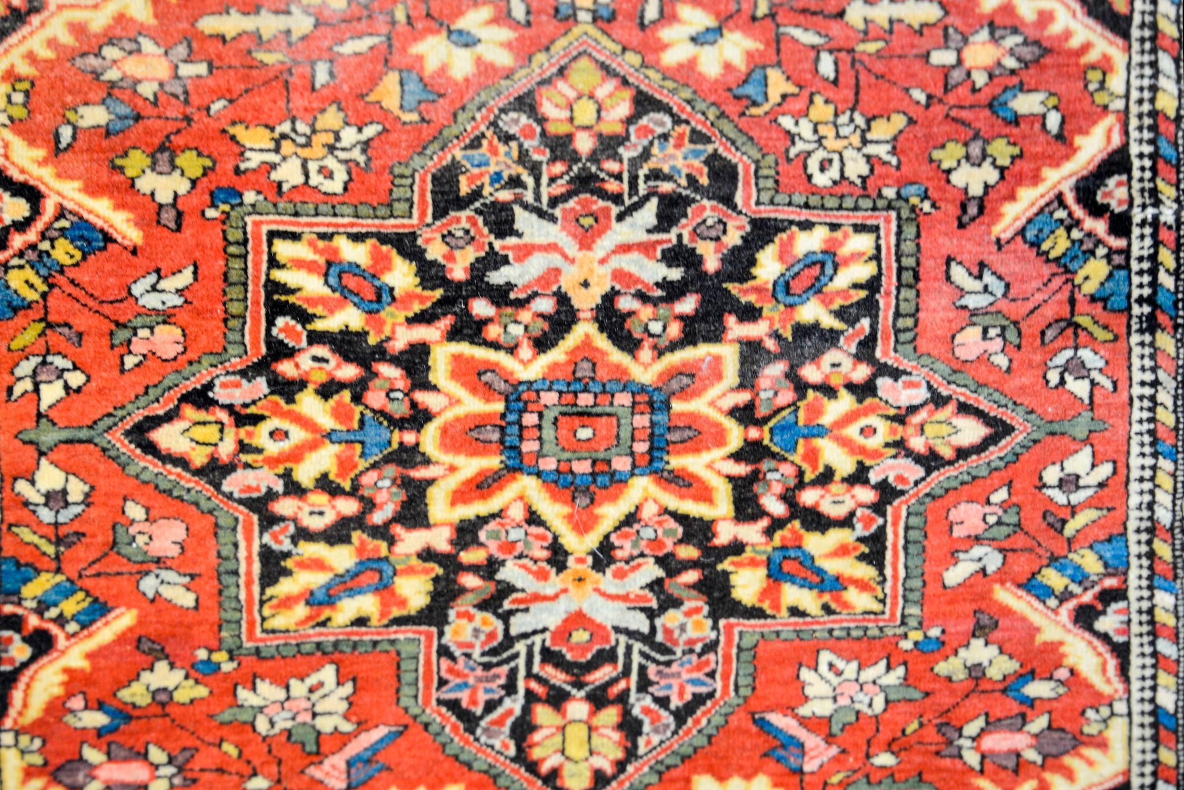 A 1930s Persian Sarouk Farahan rug with a large central medallion on a traditional stylized floral and vine patterned field woven in multicolored vegetable dyed crimson, indigo, yellow and green wool. The border is complex with multiple three