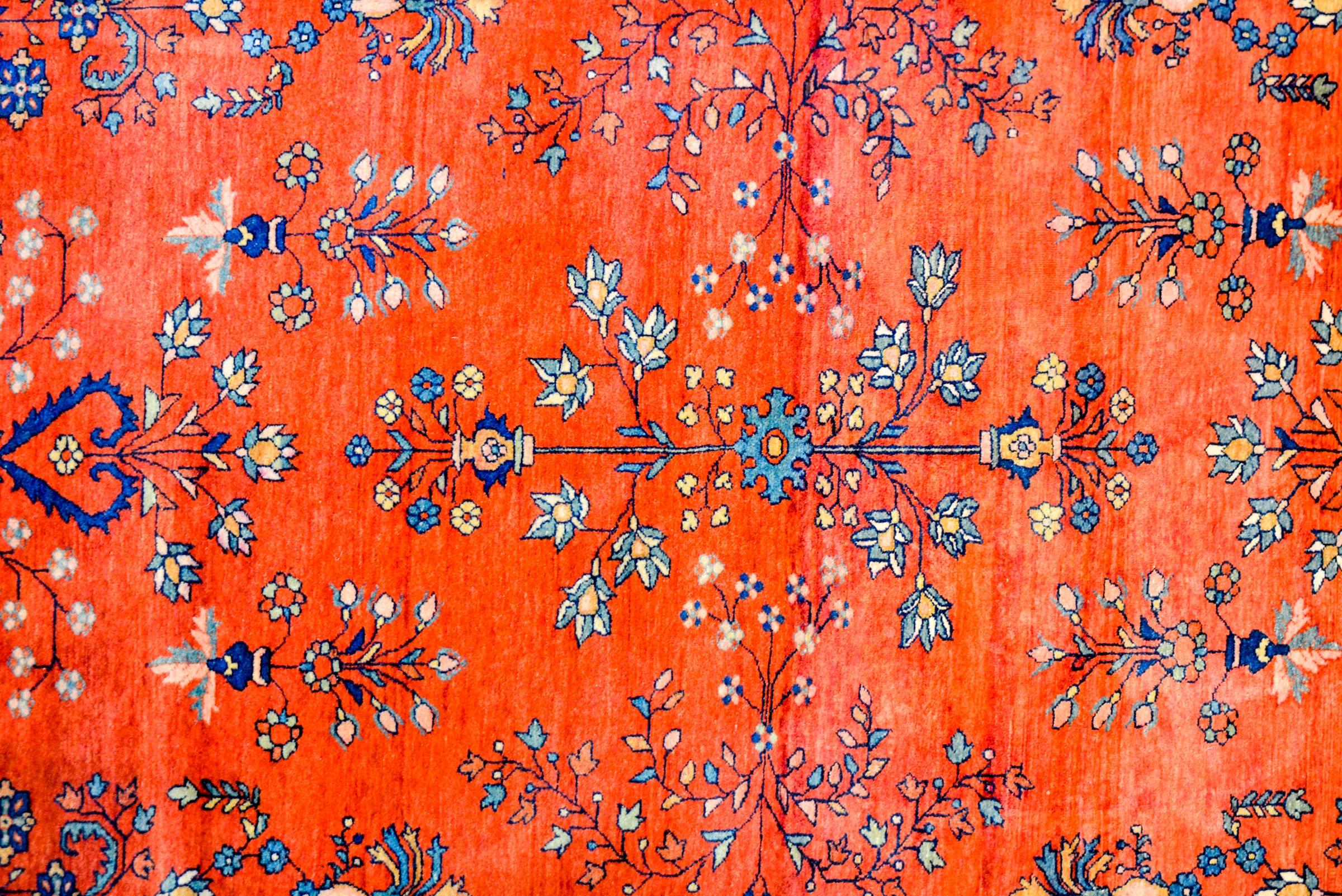 An early 20th century Persian Sarouk Farahan rug with beautiful brilliant crimson background flooded with a finely rendered field of flowers woven in light and dark indigo, and natural undyed wool. The border is exquisite, with a densely woven