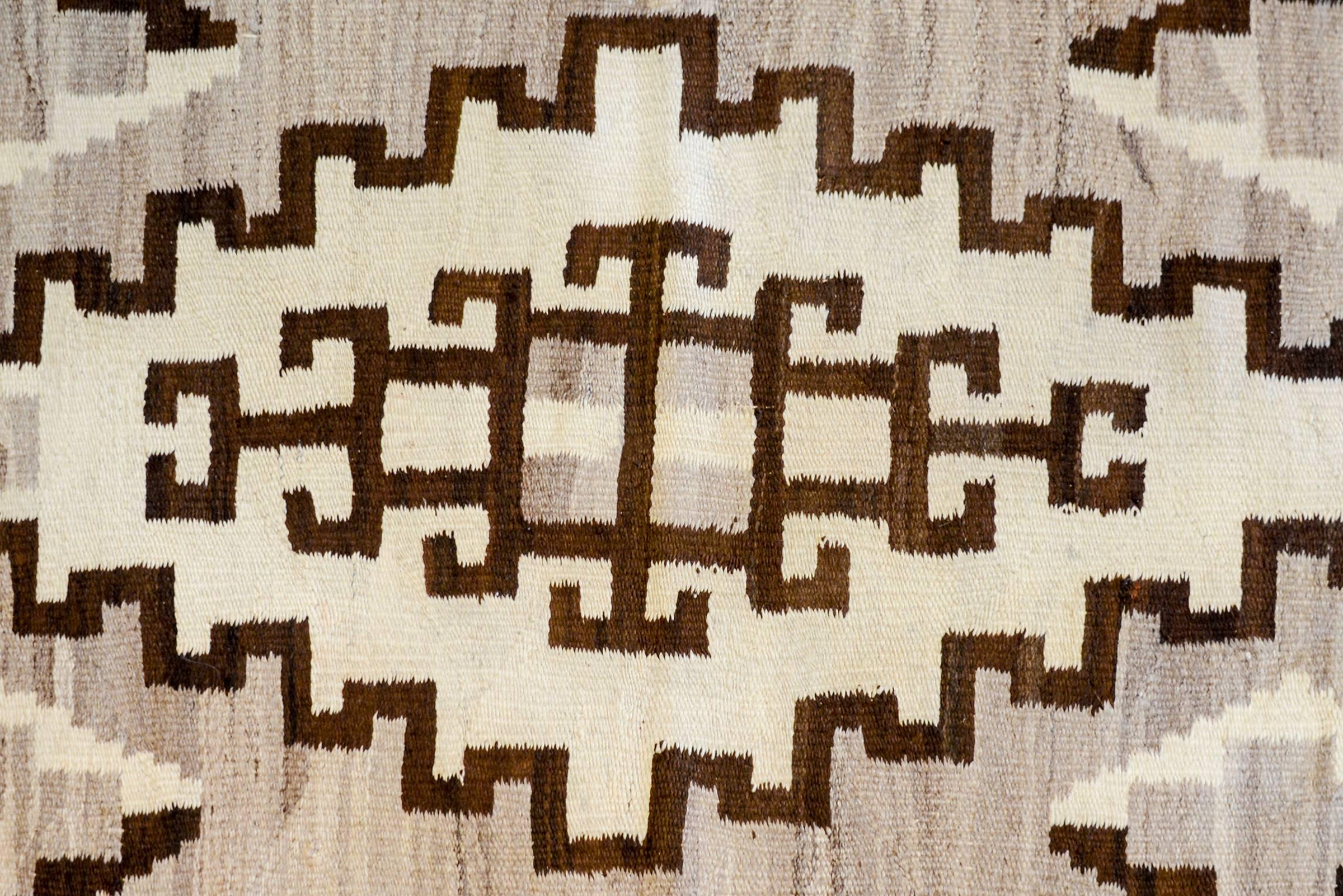 A gorgeous mid-20th century Navajo rug with a bold pattern containing large-scale diamond amidst a field of abrash natural grey and cream colored wool. The border is wide with equal width black and white stripes.