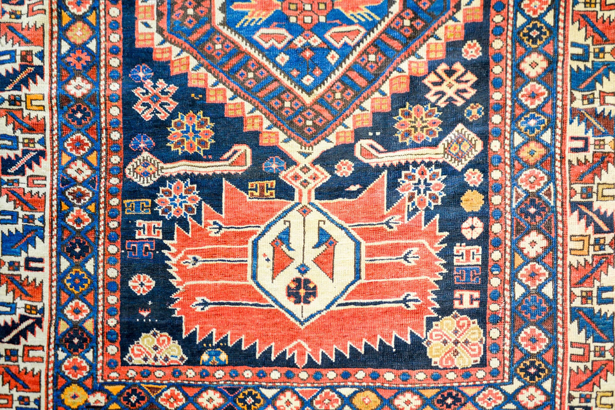 An amazing early 20th century Shirvan rug with an incredible bold and graphic stylized floral and leaf patterns woven in rich crimson, gold, and white on a deep indigo background amidst a field of multicolored flowers woven in complementary colors.