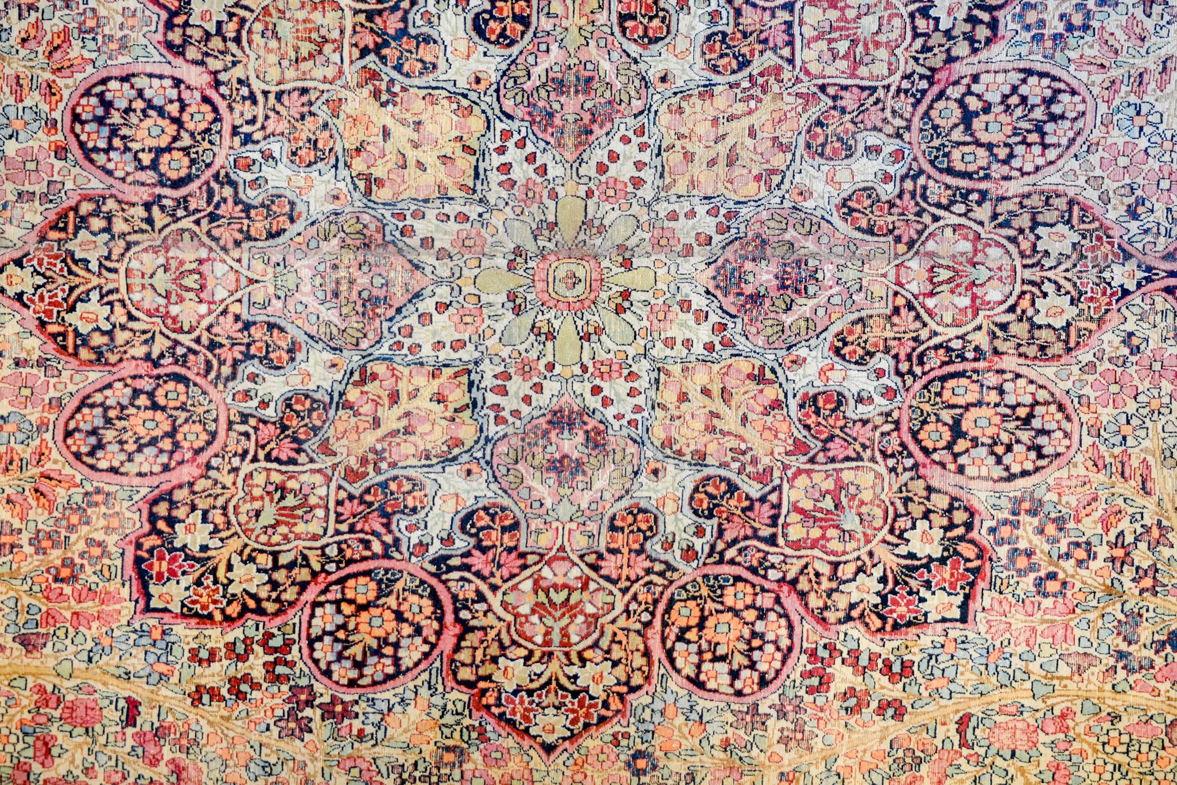An incredible early 20th century Persian Lavar Kirman rug with a beautiful central medallion, each lobe woven with a different flower. The medallion lives amidst a field of intensely woven field of flowers and vines. The border is wide with a large