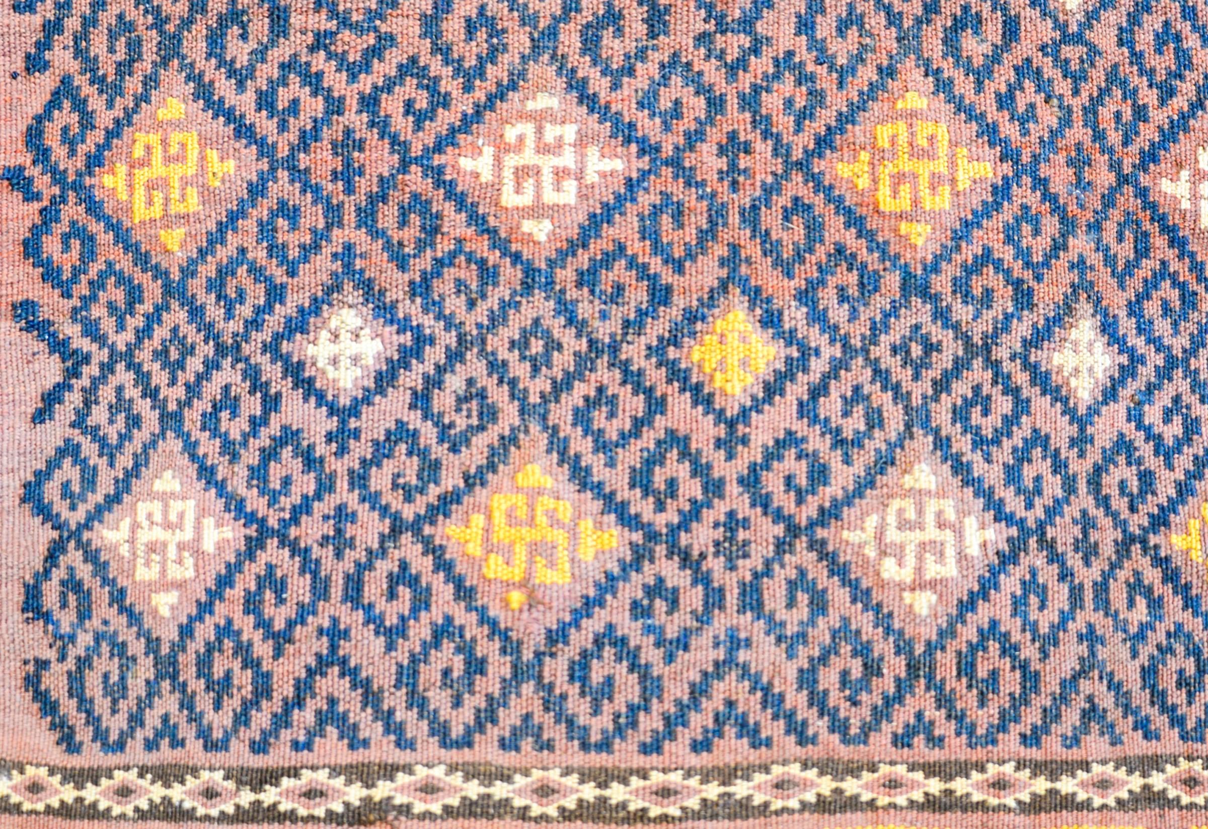 A wonderful early 20th century Uzbek Sumak bag face rug with a wonderful pattern containing an all-over geometric form woven in indigo, yellow, and white, on a pale lavender background. The border is complex, with two petite stylized floral stripes,