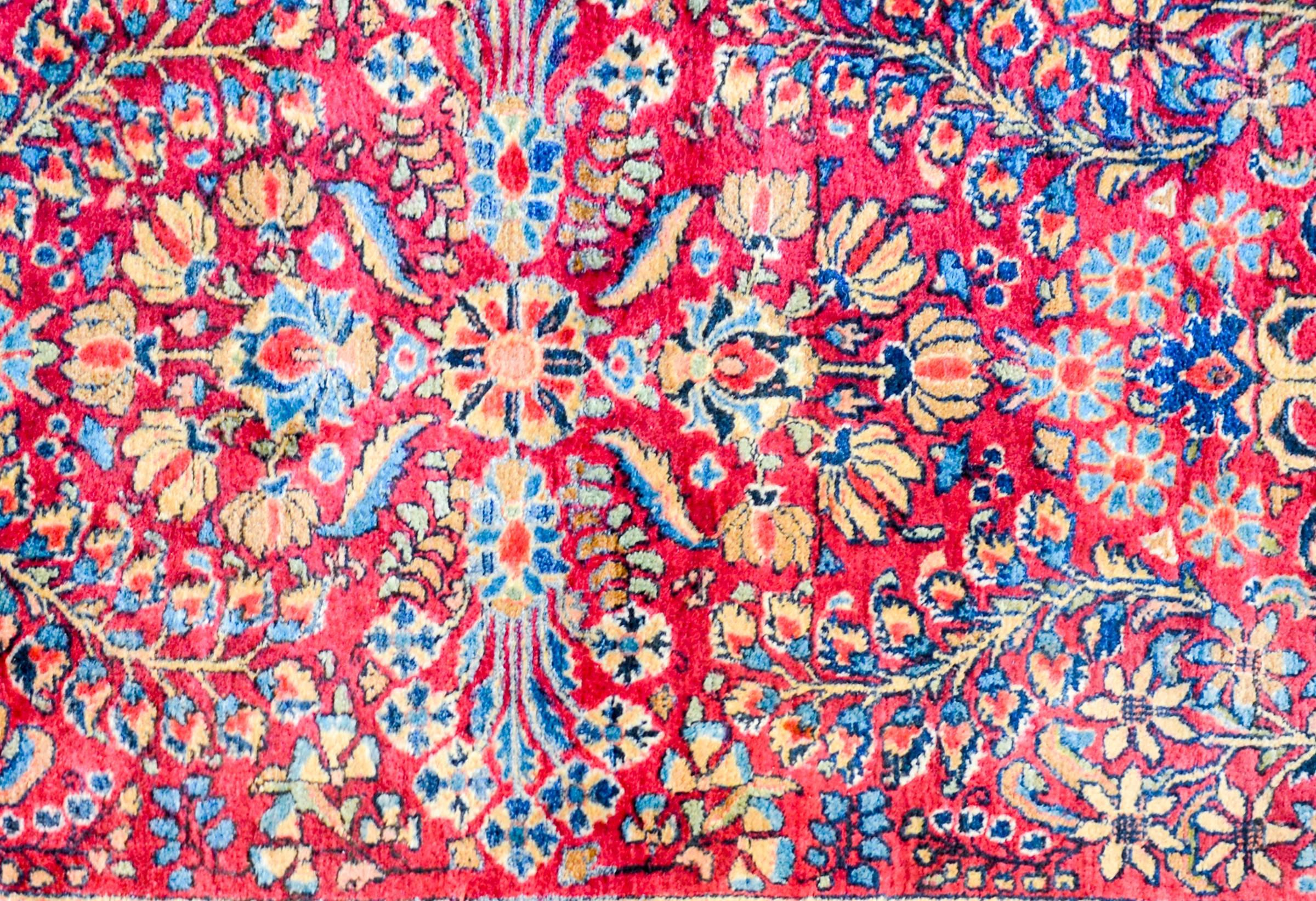 Ein schöner persischer Sarouk-Teppich aus dem frühen 20. Jahrhundert mit einem fantastischen, gespiegelten Blumen- und Rankenmuster, das fachmännisch in hellem und dunklem Indigo, Rosa, Gold und natürlicher, ungefärbter Wolle auf einem kräftigen