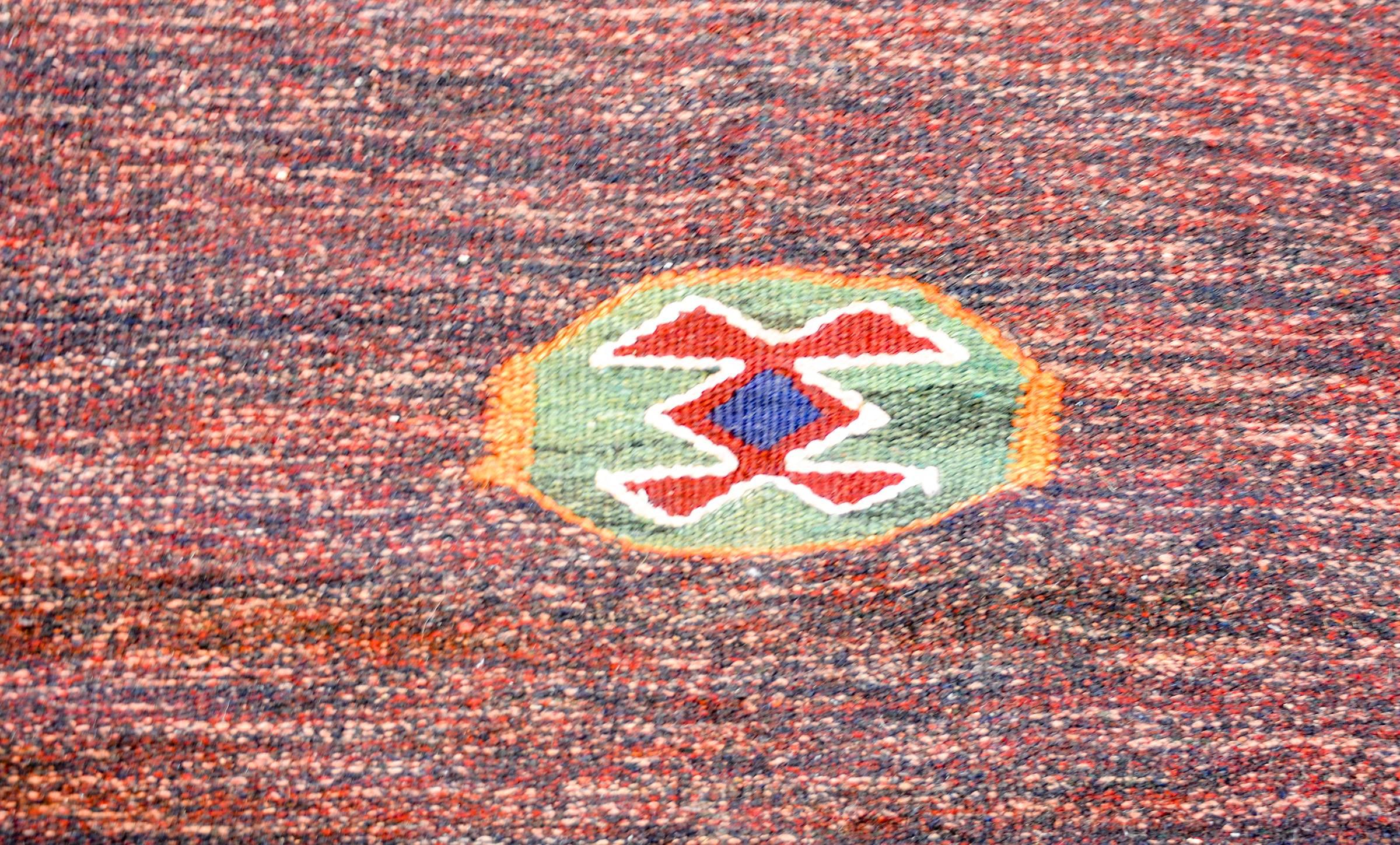 Ein unglaublicher alter persischer Gabbeh-Kilim-Teppich aus karmesinroter und indigoblauer Wolle mit einem asymmetrischen Muster aus zwei weißen Streifen und einem zentralen stilisierten Blumenmedaillon.
