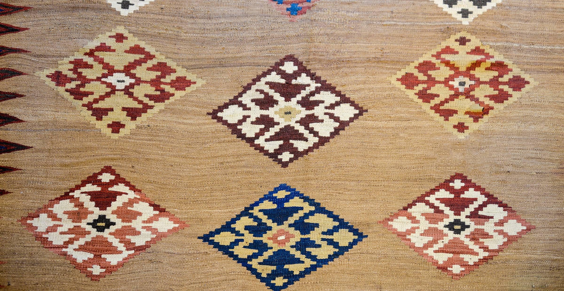 A memorable early 20th century Persian Azeri Kilim rug with one large diamond medallion flanked by multiple smaller diamond medallions woven in multicolored vegetable dyed wool, on an incredible natural undyed abrash camel hair background. The