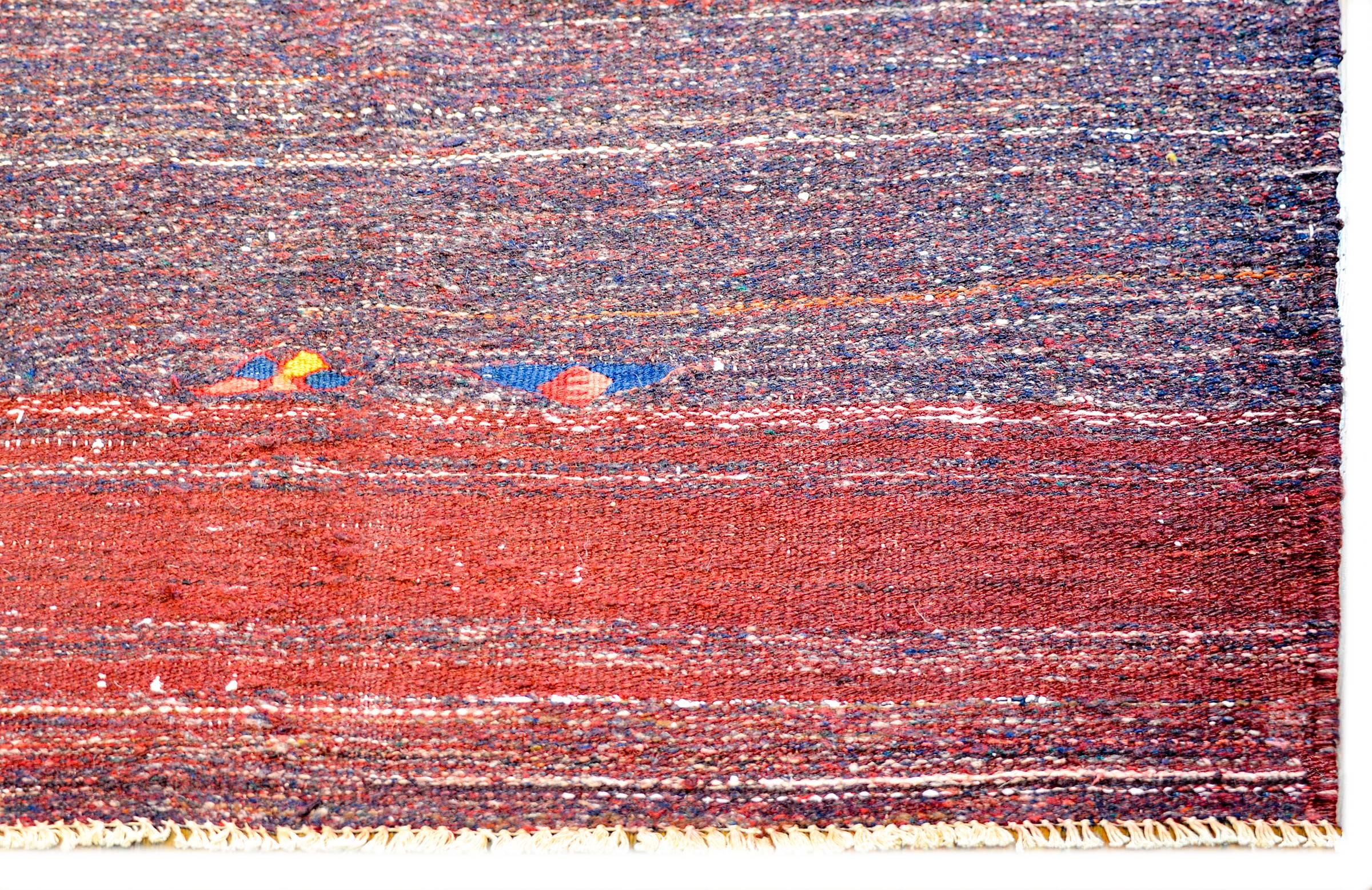 An incredible vintage Persian Gabbeh Kilim rug woven in crimson and indigo wool with a simple whipstitched edge trim.