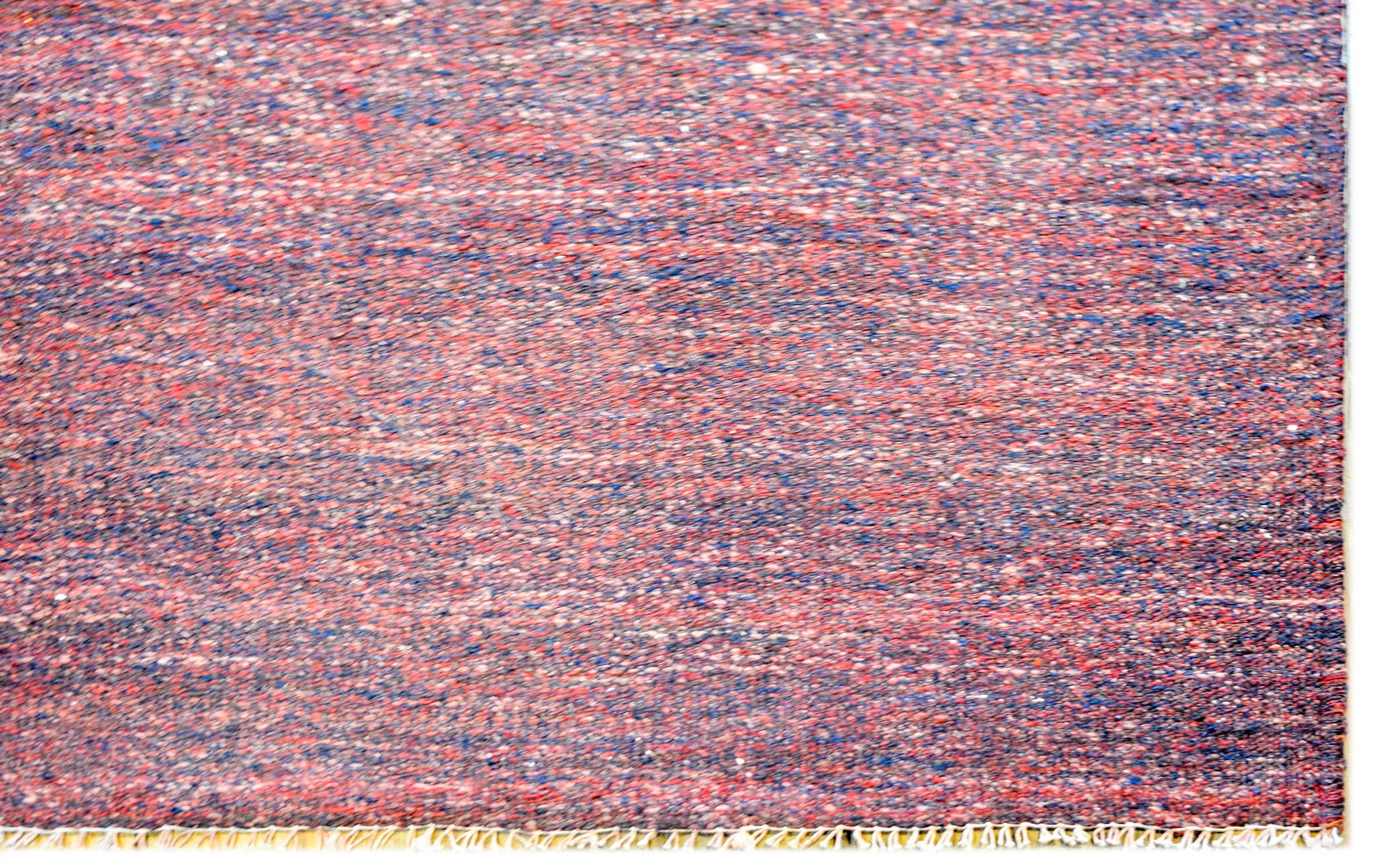 A fantastic vintage Persian Gabbeh Kilim rug woven in crimson and indigo wool with a simple whipstitched edge trim.